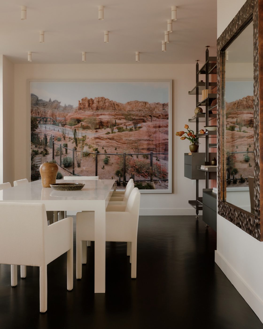 Dining room in nearly all white minimalist loft apartment in New York's West Village  designed by Clive Lonstein and featuring a Thomas Struth photograph plays a starring role in the dining area, where sleek contemporary chairs sit at a custom lacquered table designed by Lonstein. The mirror is by Robert Kuo