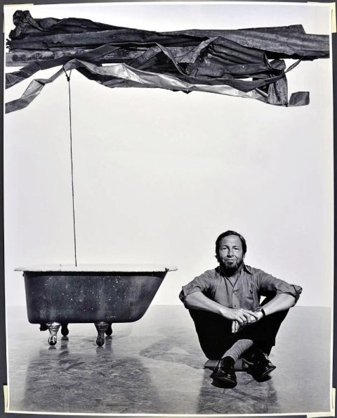 Robert Rauschenberg sits on the floor of MoMA with his sculpture "Sor Aqua," in a 1977 portrait by Jack Mitchell.