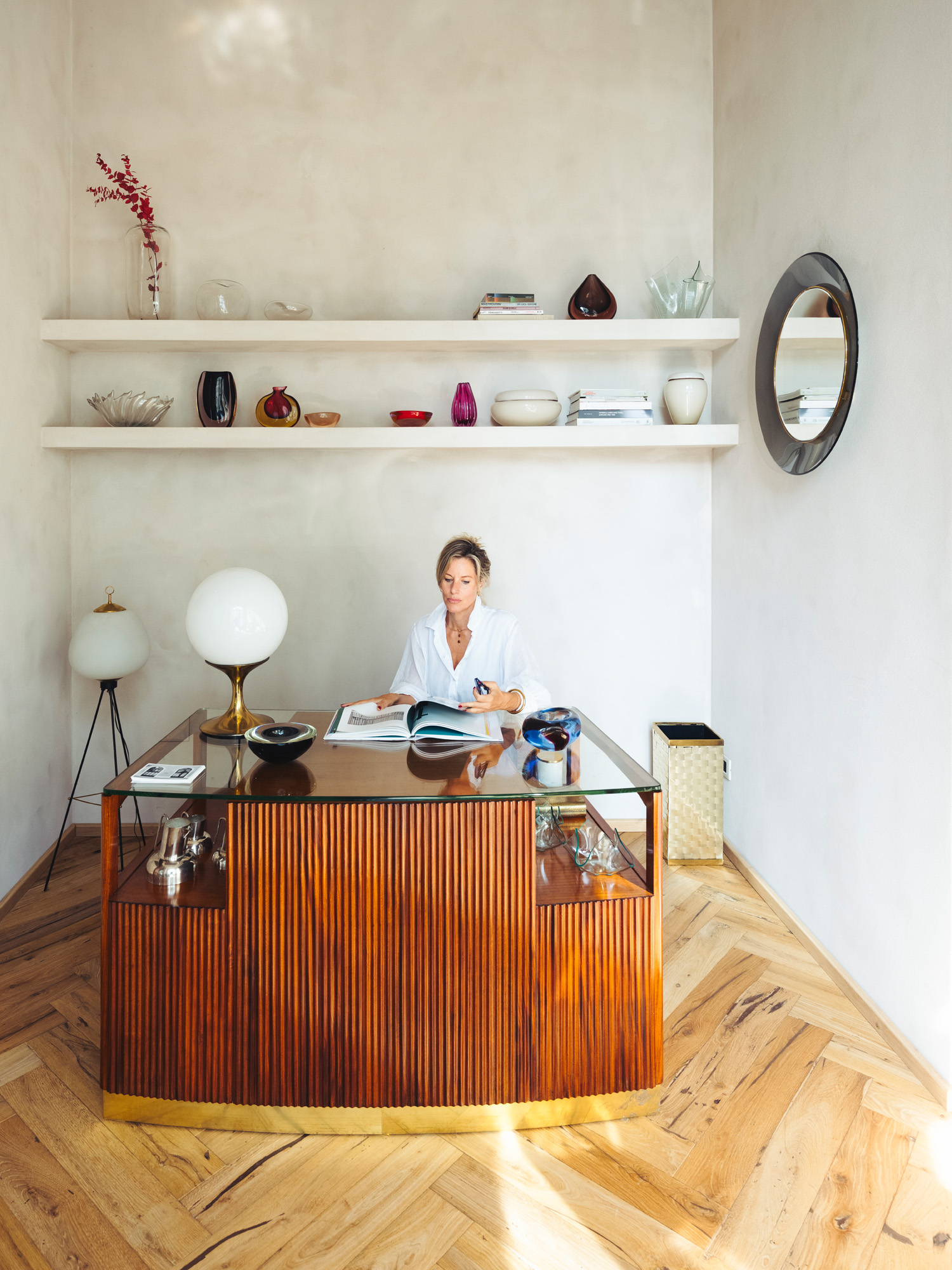 Antiques dealer Bec Astley Clarke sitting behind a curving Paolo Buffa desk in her shop The Italian Collector in Florence, Italy's Oltrarno neighborhood