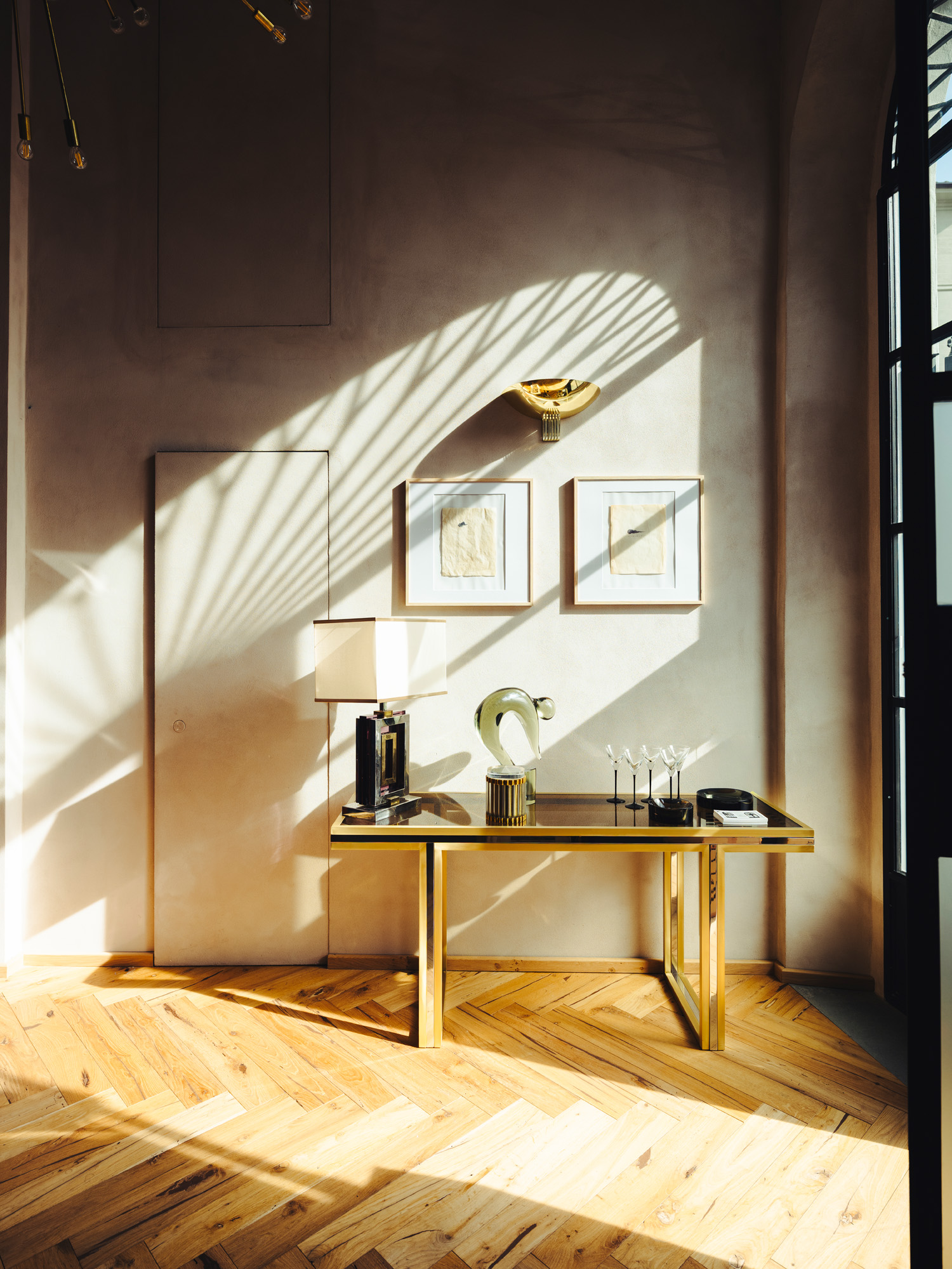 Gio Ponti Cloud sketches hanging on wall over a 1970s brass-and-glass console table by Romeo Rega topped by a glass Rega lamp and long-stemmed martini glasses, all at the Italian Collector, the Florence Italy shop of antiques dealer Bec Astley Clarke