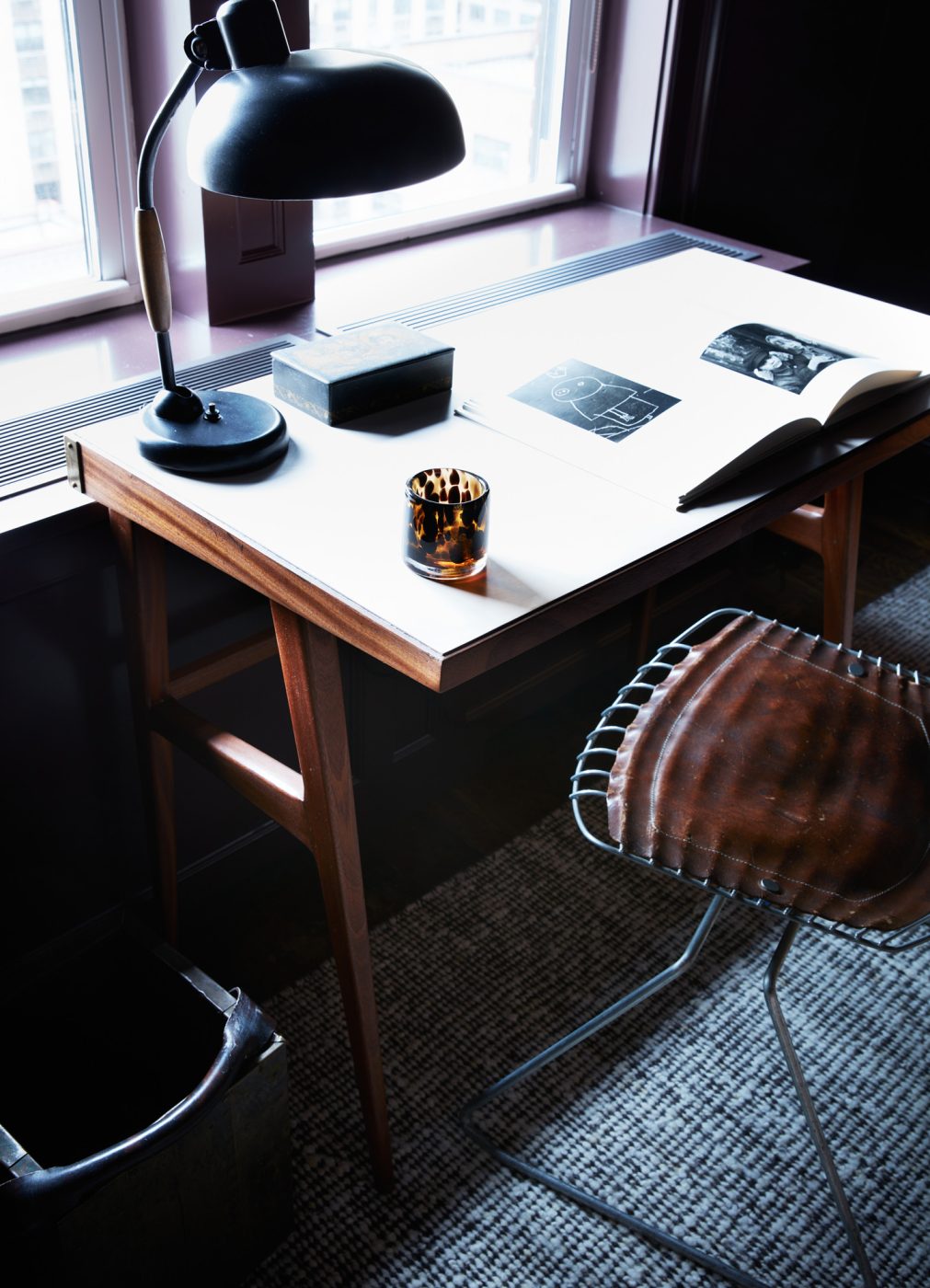 Desk area with a gridded-metal Beaubourg chair by Michel Cadestin and Georges Laurent a mid-century Fratelli Strada desk, and  lamp by Christian Dell for Koranda Austria in the eggplant-colored office of an apartment on New York's Upper East Side designed by Erik Gensler