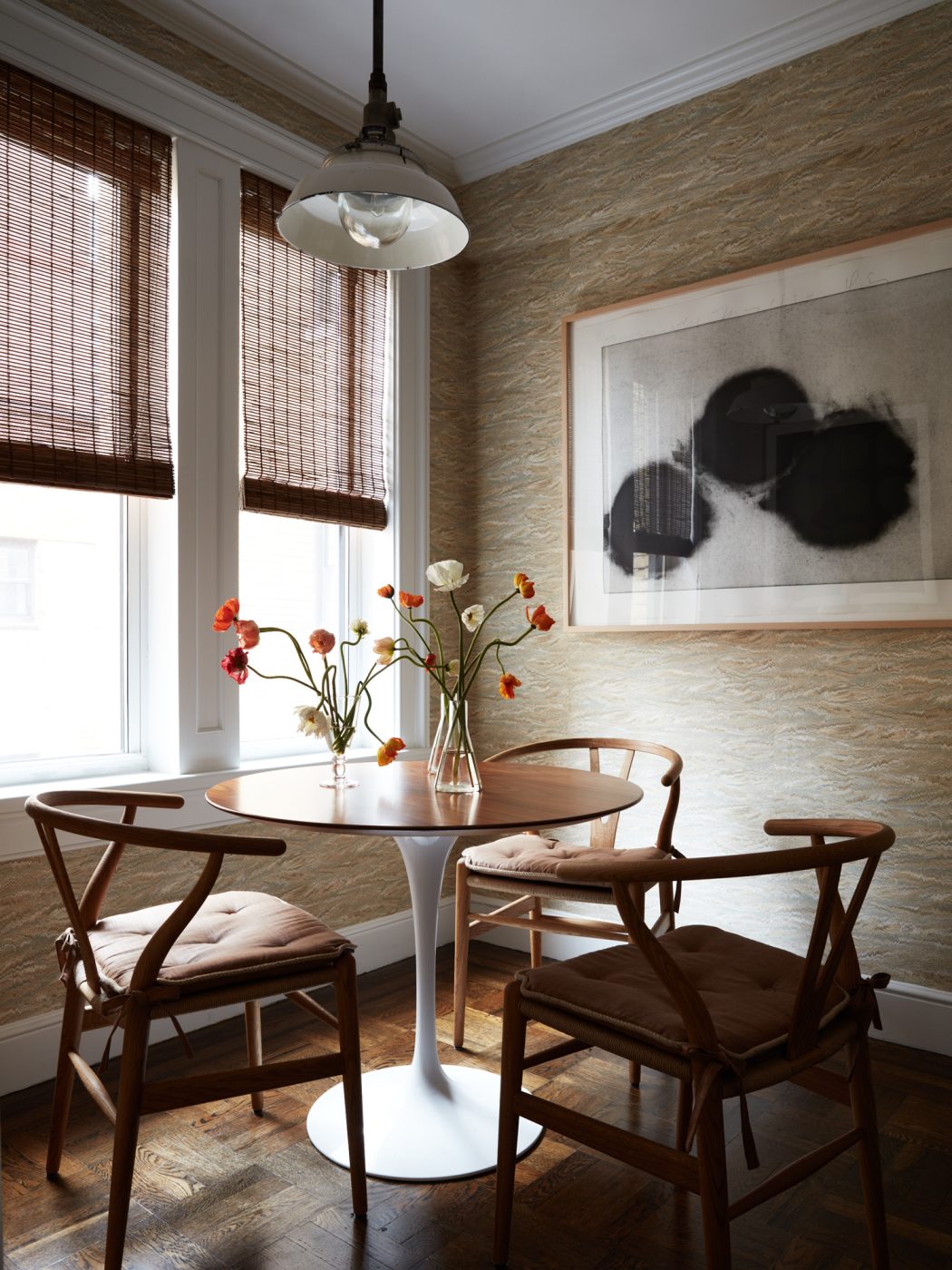 Table area in the kitchen of an apartment on New York's Upper East Side designed by Erik Gensler featuring Wishbone chairs by Hans Wegner surrounding an Eero Saarinen Tulip table. pendant light above is from Aero.
