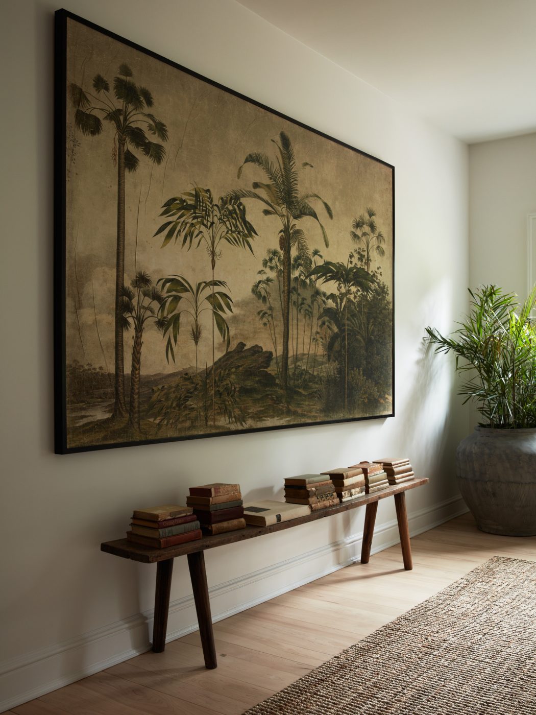 Stair landing in Upstate New York home designed by Maggie Smith with a botanical tapestry from Montana Labelle hangs over a wooden bench from Adrianna Shamaris