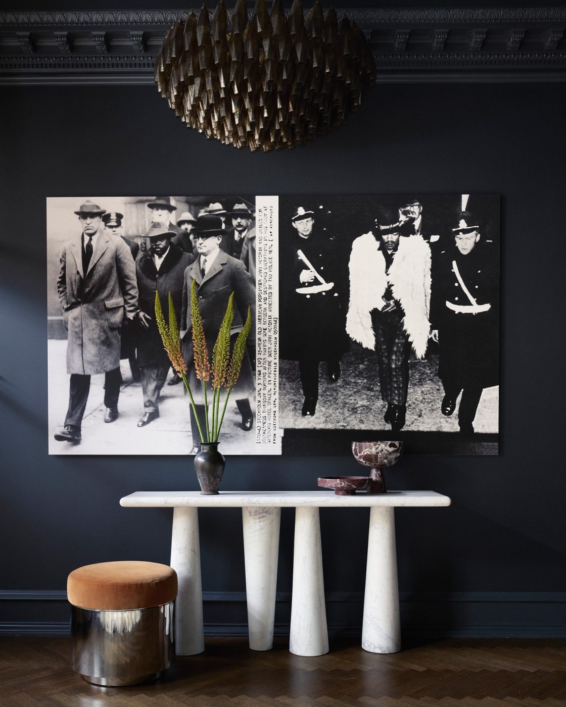 Marble console table, Arthur Jaffa artwork and mid-century stool agains a dark blue wall in entry area of living room of Harlem townhouse designed by Crystal Sinclair
