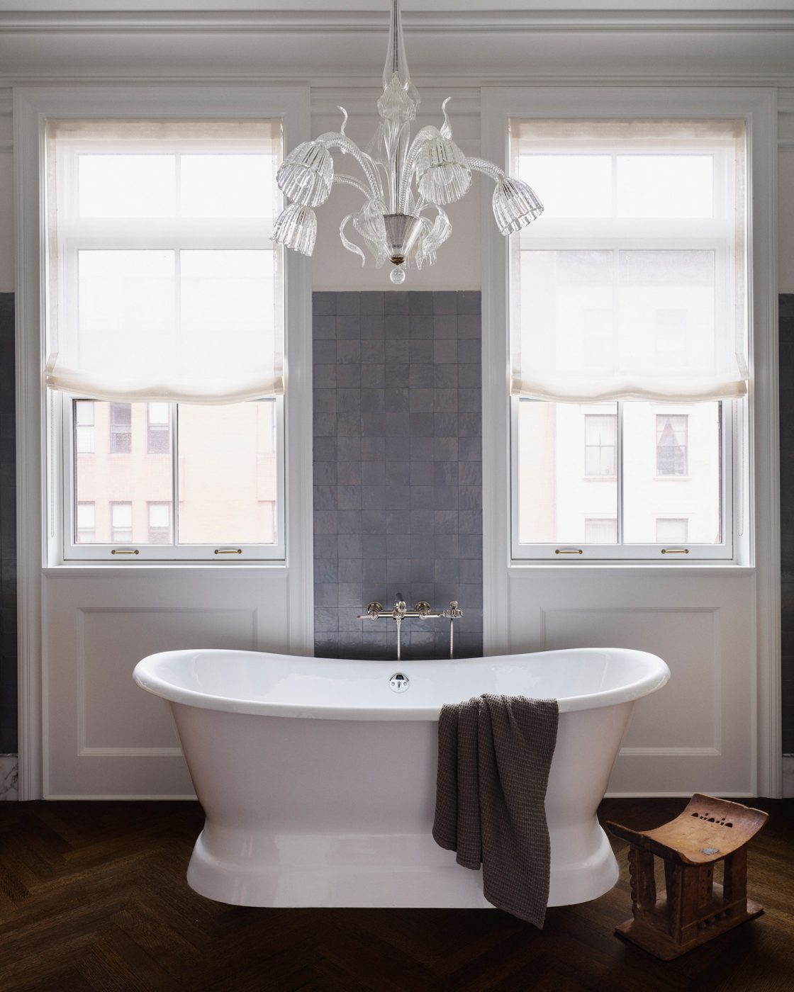 Soaking tub under Murano glass chandelier in primary bathroom n a Harlem townhouse design by Crystal Sinclair
