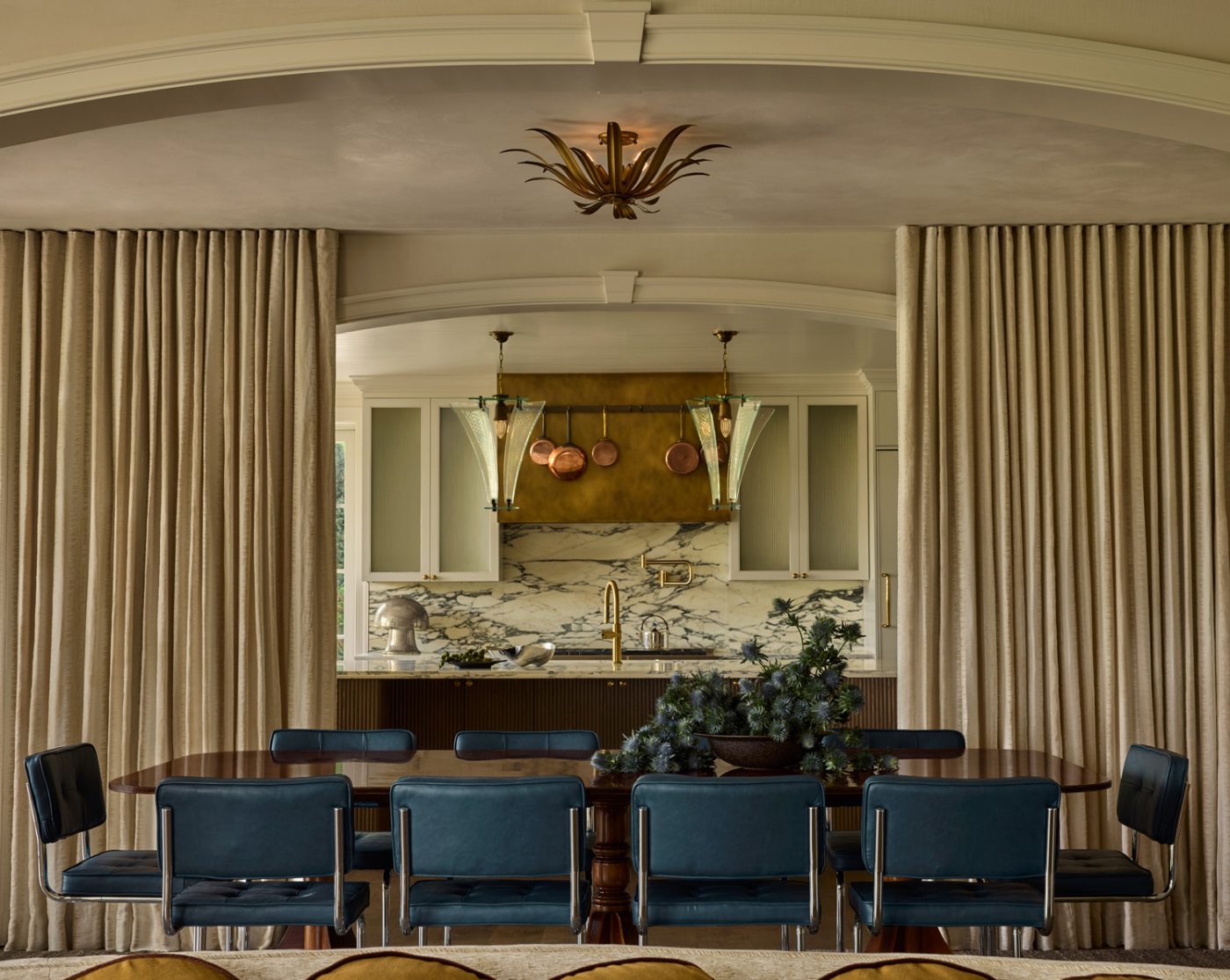 Tubular steel chairs at highly polished wooden rectangular table with curtained walls in the dining room of a 1912 Colonial-style home redesigned by Autumn Oser and Andre Golsorkhi, partners in the design firm Haldon House