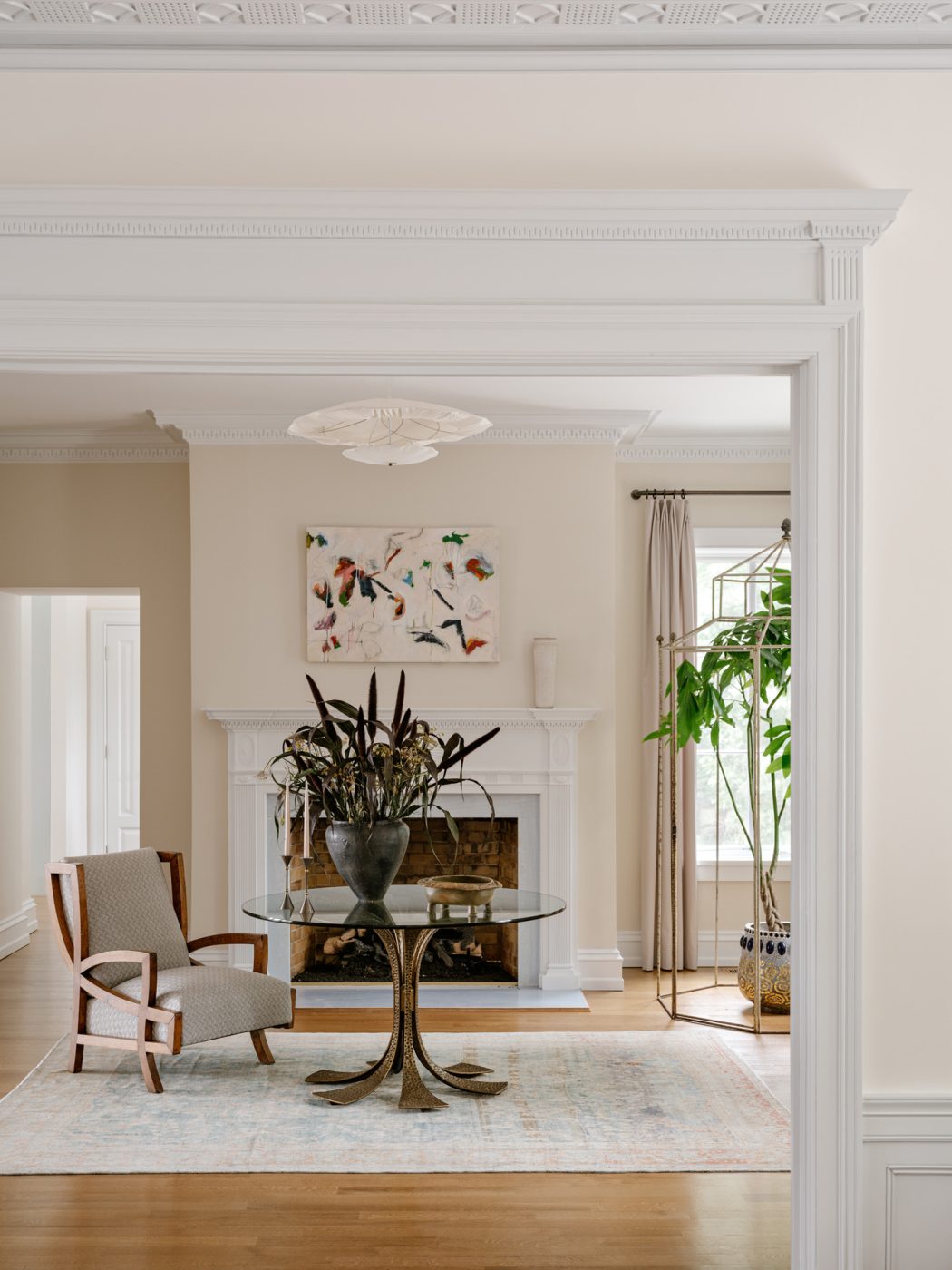 Reception room with glass-topped bronze center table and 1940s Italian lounge chair in front of fireplace in a Long Island home with interiors by studio Evan Edward designers Michael Edward Moirano and Josh Evan Goldfarb