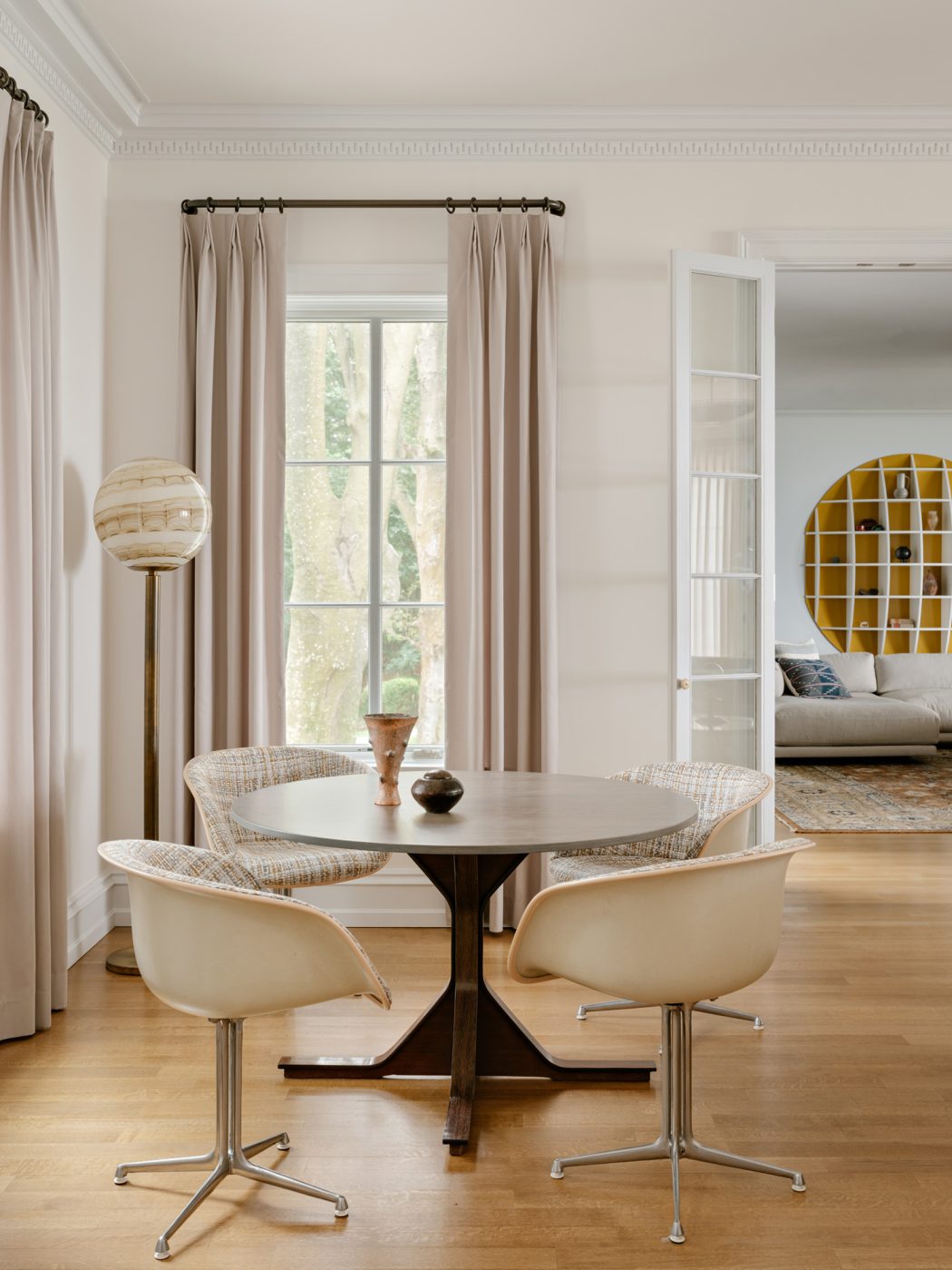 Living room corner with Gianfranco Frattini games table, Charles and Ray Eames fiberglass chairs, and a vintage Murano-Glass floor lamp in the living room of a Long Island home with interiors by studio Evan Edward designers Michael Edward Moirano and Josh Evan Goldfarb