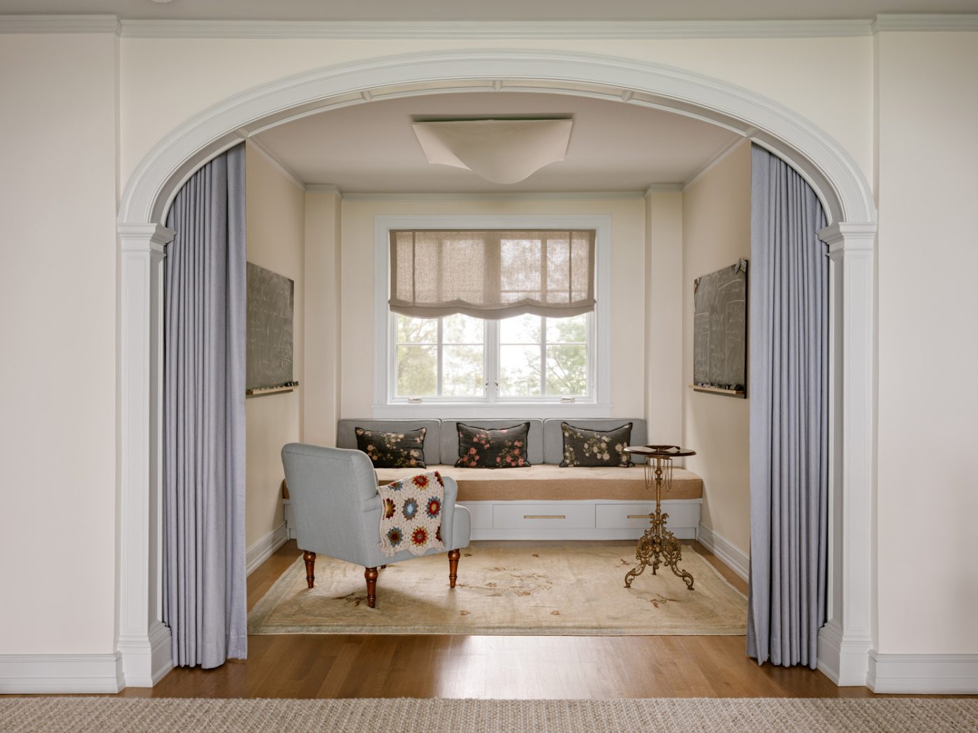 A seating nook with built-in daybed banquette in a curtained alcove of a Long Island home with interiors by studio Evan Edward designers Michael Edward Moirano and Josh Evan Goldfarb