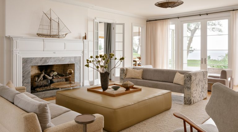 Sofas facing a large coffee table in front of the fireplace with mantel topped by a Curtis Jere sailboat sculpture in the living room of a Long Island home with interiors by studio Evan Edward designers Michael Edward Moirano and Josh Evan Goldfarb