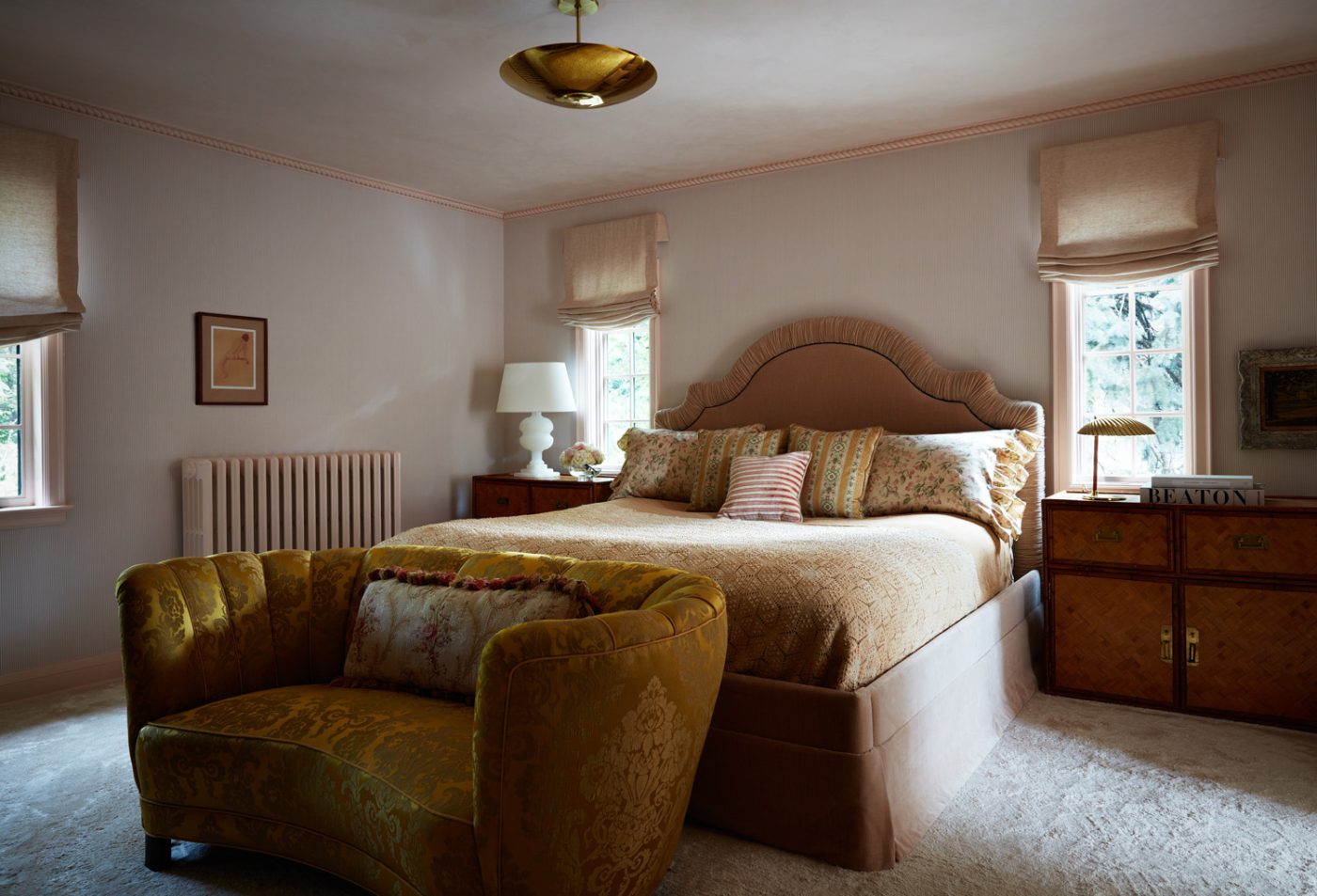 Striped Schumacher wallpaper, upholstered George Smith bed, vintage wicker-and-faux-bamboo nightstands and a Lawson-Fenning pendant in the primary bedroom of a Mediterranean-style house in Minneapolis, Minnesota