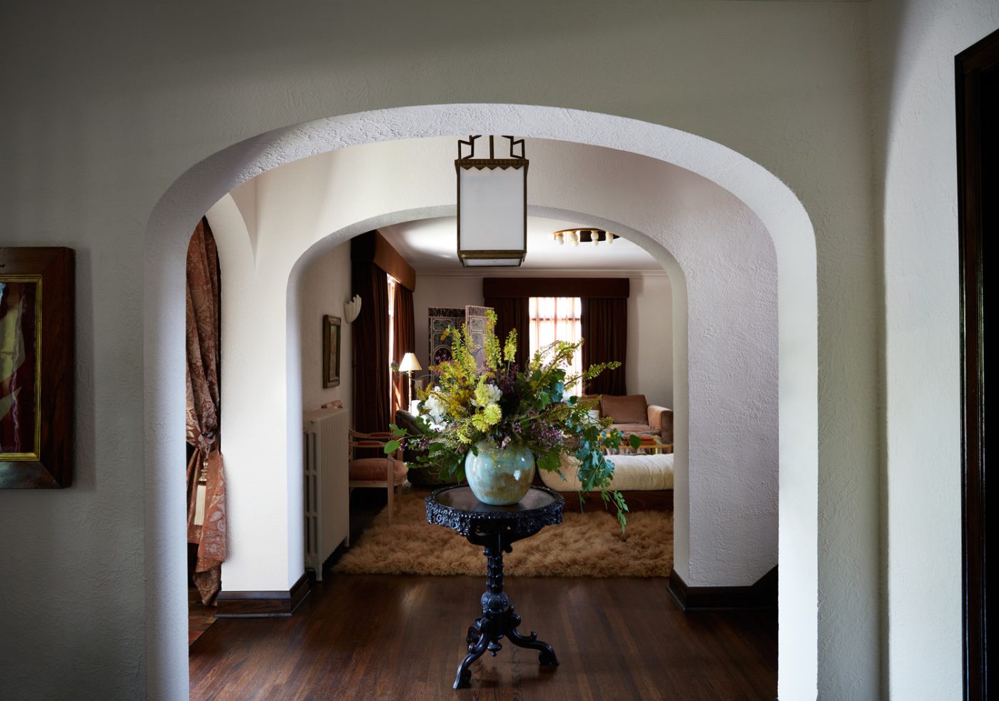 Antique lantern hanging over a Scottish side table from Obsolete in the entry of a Mediterranean-style house in Minneapolis, Minnesota