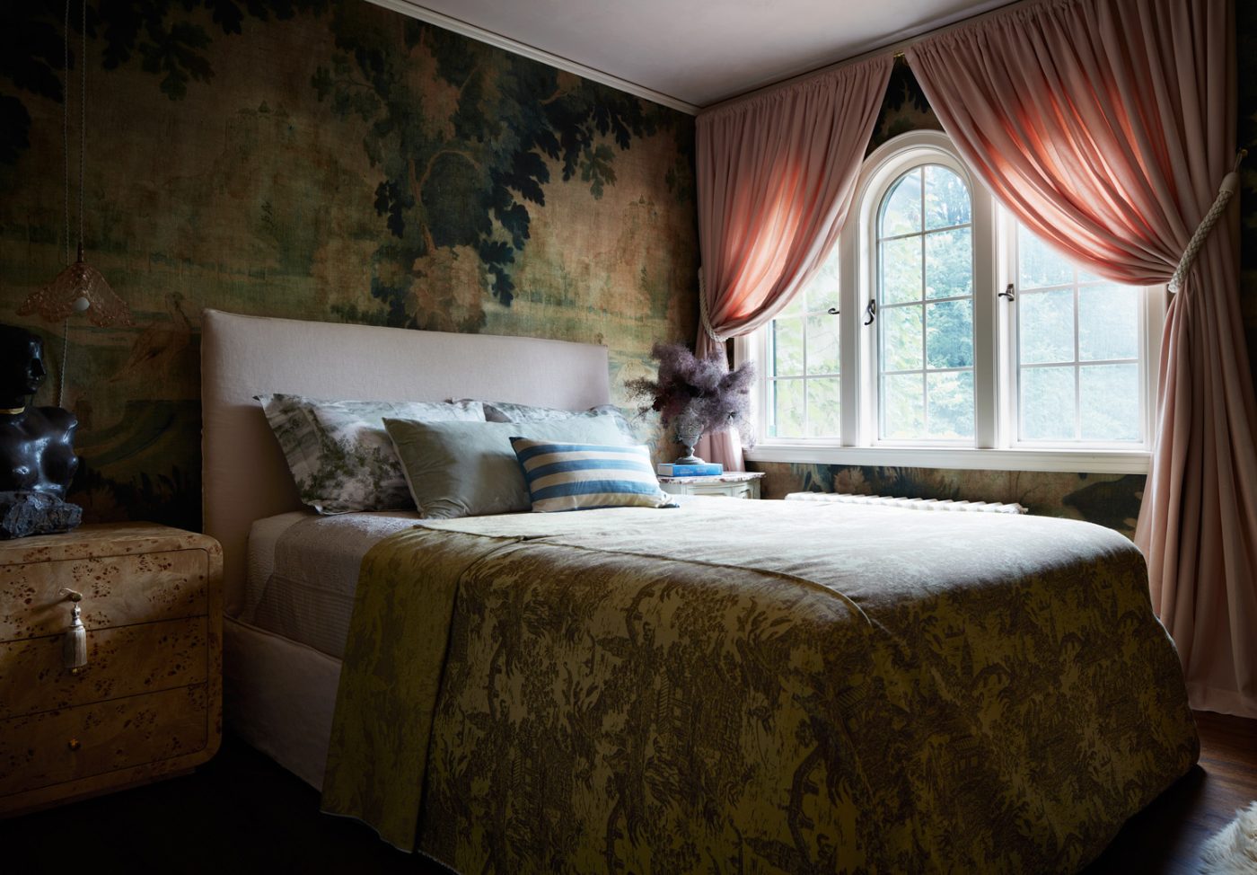 A Pierre Frey enchanted forest wallpaper and swagged pink drapes in the guest bedroom of a Mediterranean-style house in Minneapolis, Minnesota