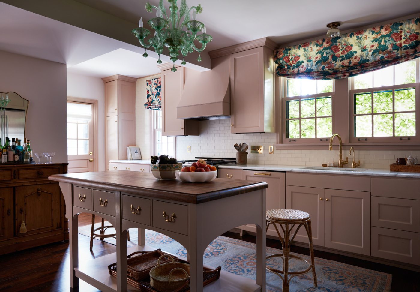 Kitchen with pale-pink cabinets and antique details and furniture in a Mediterranean-style house in Minneapolis, Minnesota