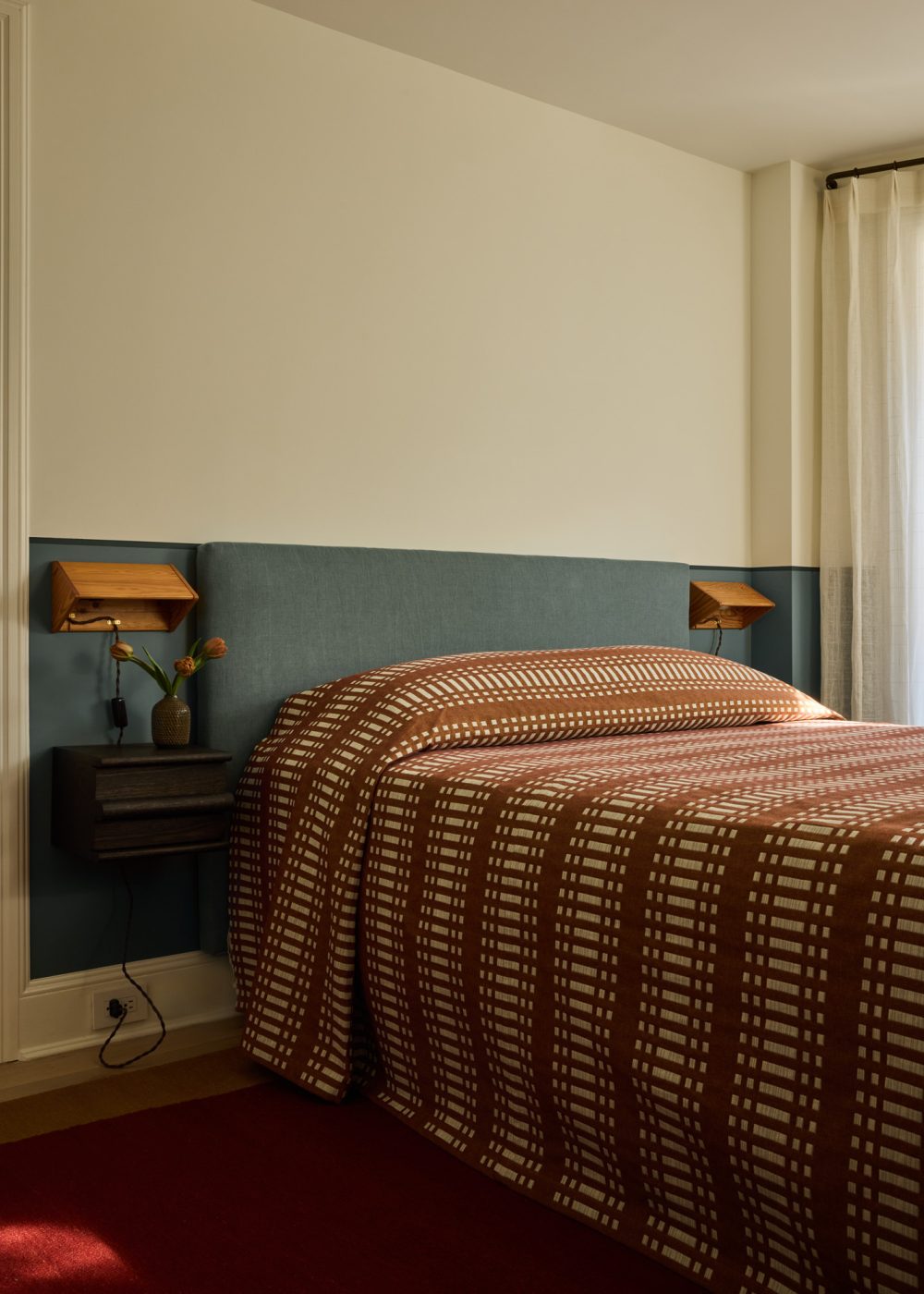 Guest bedroom with upholstered headboard in patterned rust coverlet in Prospect Heights Brooklyn brownstone renovated by the interior design firm Jesse Parris-Lamb
