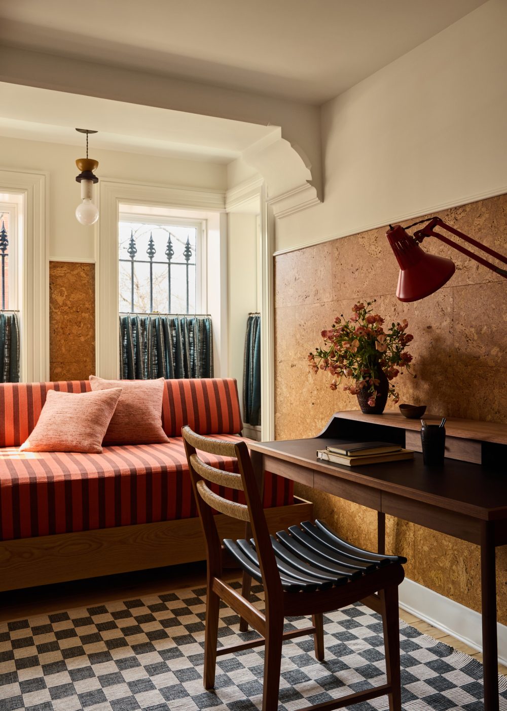 Garden level home office with cork-covered wall, daybed in window bay and dark wood desk and chair in Prospect Heights Brooklyn brownstone renovated by the interior design firm Jesse Parris-Lamb