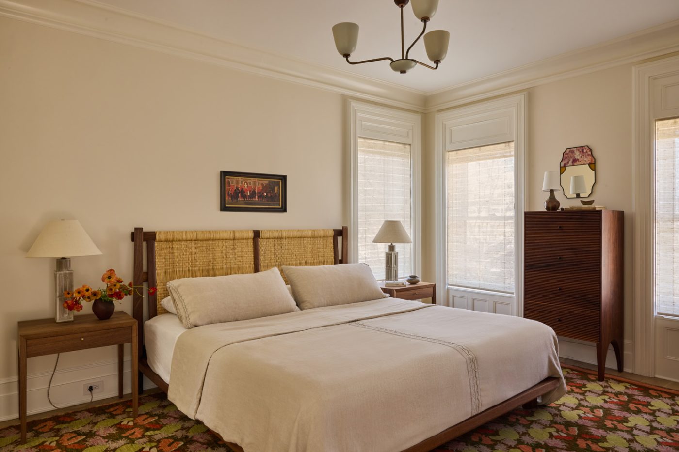 Primary bedroom with woven rush headboard, tall dresser, simple nightstands and ceramic lamps in Prospect Heights Brooklyn brownstone renovated by the interior design firm Jesse Parris-Lamb