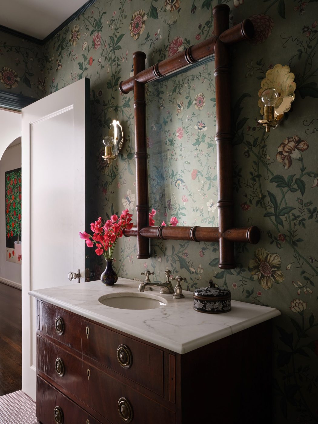 Powder room with grey-gree floral wallpaper , antique chest turne dinto marble-topped vanity, and bamboo framed mirror in a Spanish Colonial house in Highland Park Village Dallas designed by Dafna Kikuchi of Daf&Co