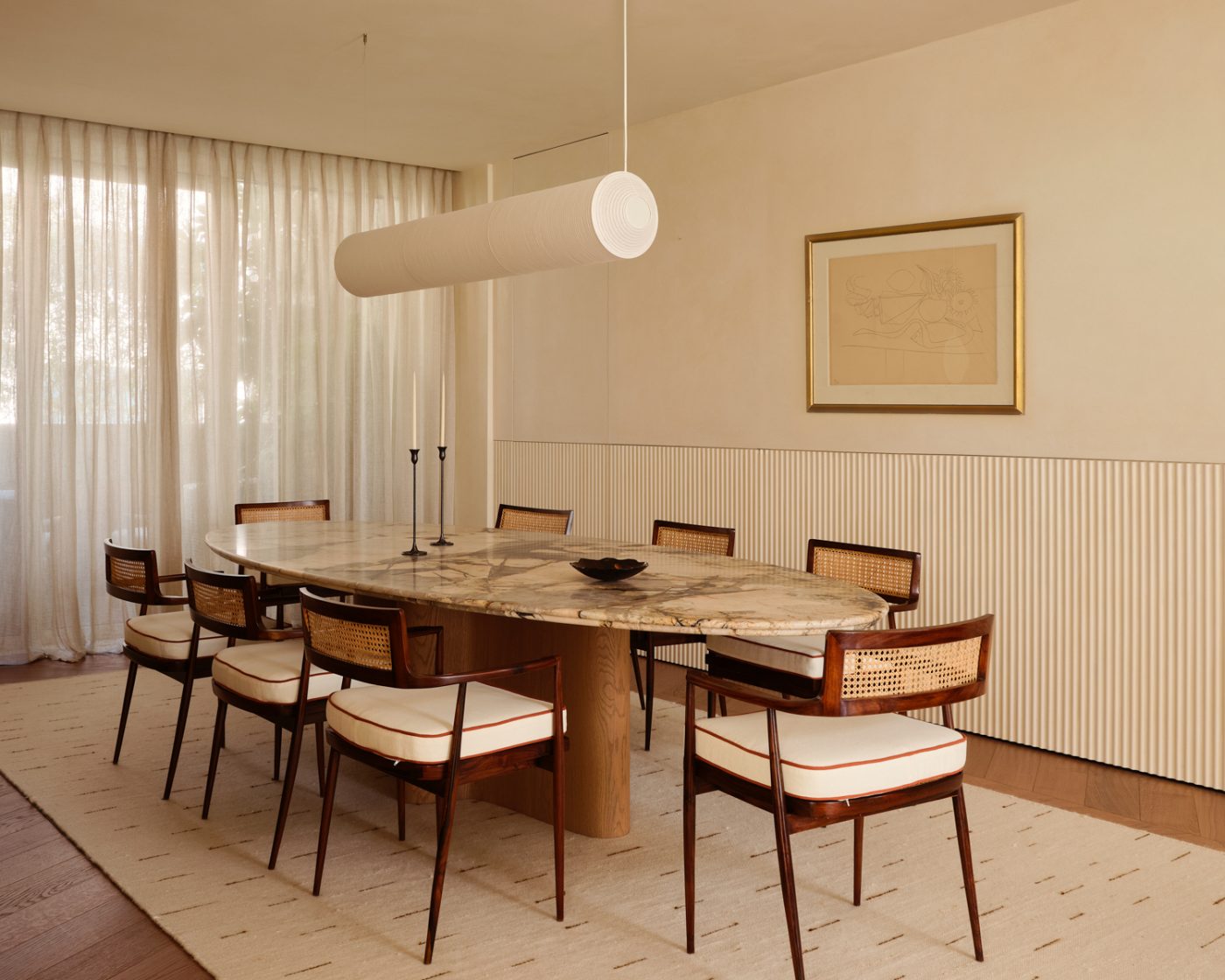 dining room with Joaquim Tenreiro chairs around a marble topped oval table in a Milan penthouse whose interiors are by Edo Mapelli Mozzi, founder of the design and development firm Banda.