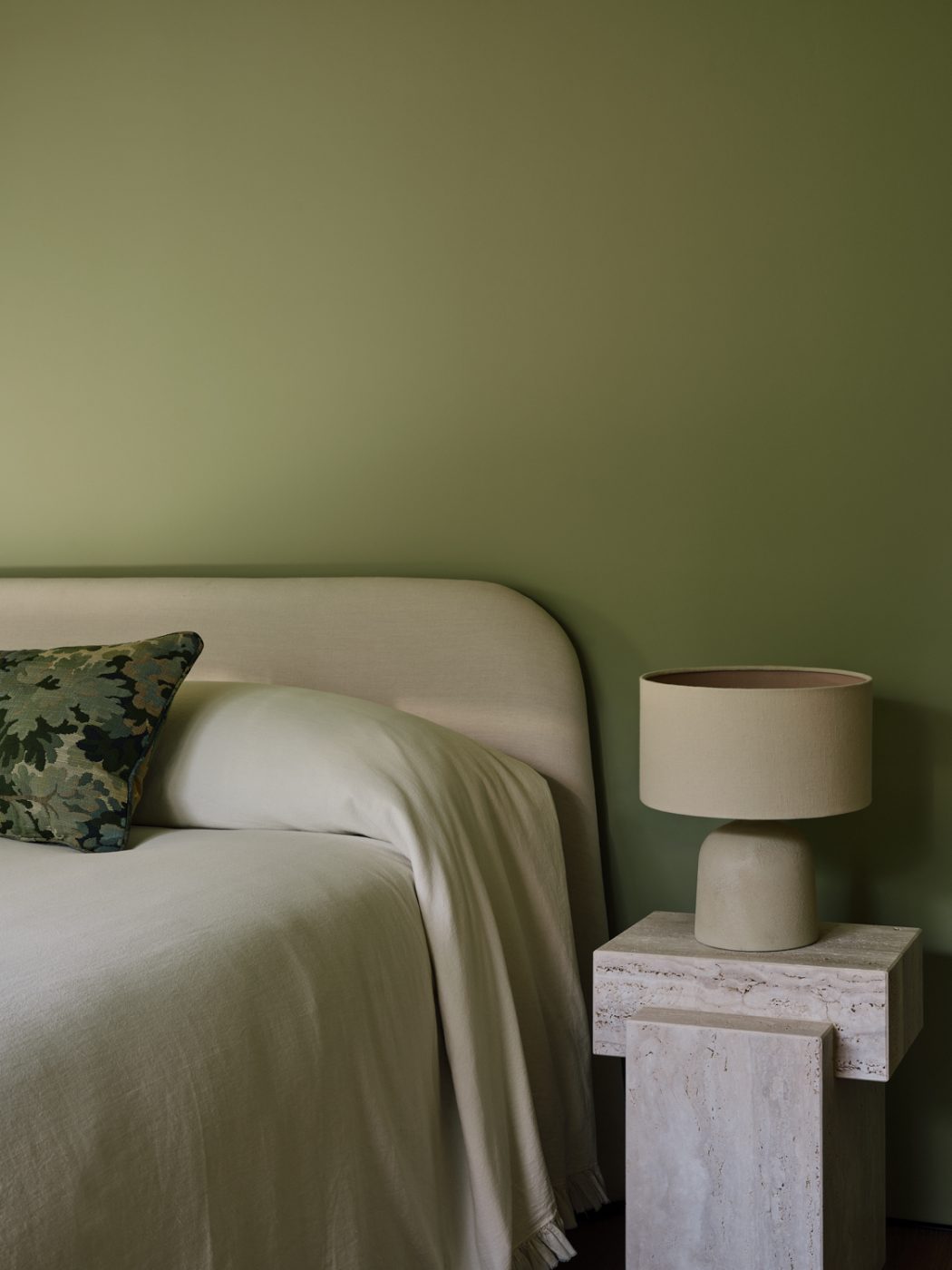 Green-walled guest room with a ivory upholsterd bed and travertine nightstands in a Milan penthouse whose interiors are by Edo Mapelli Mozzi, founder of the design and development firm Banda.