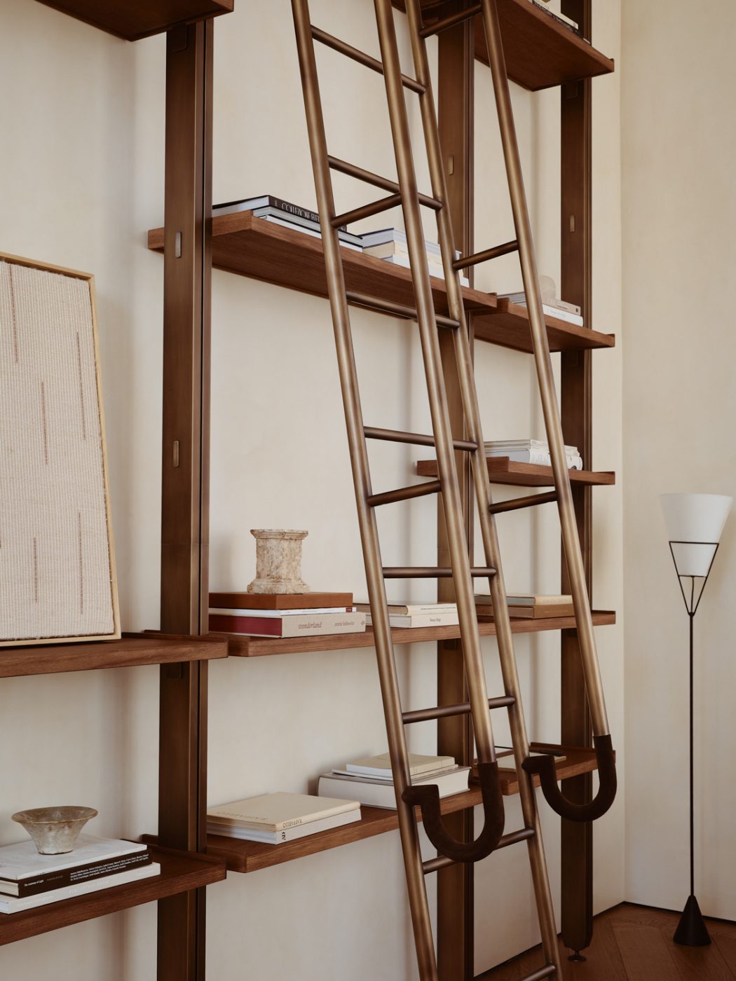 Living built-in wood-and-brass mid-century-inspired wall bookshelf in a Milan penthouse whose interiors are by Edo Mapelli Mozzi, founder of the design and development firm Banda.
