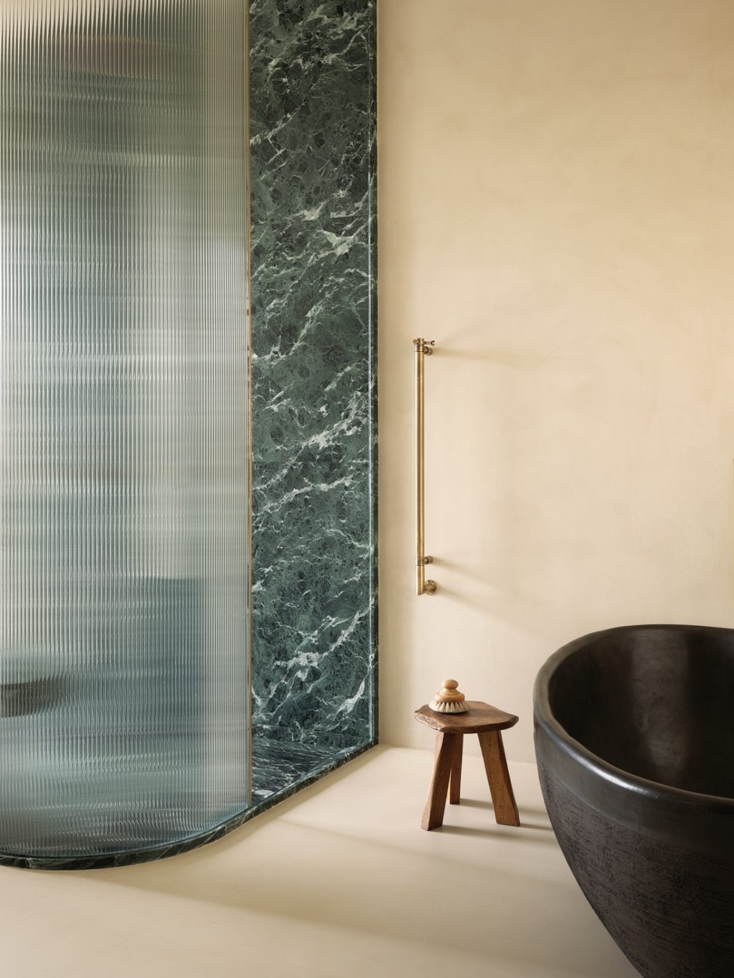 vintage Pierre Jeanneret desk and Plaster and green marble bathroom in the primary suite of a Milan penthouse whose interiors are by Edo Mapelli Mozzi, founder of the design and development firm Banda.