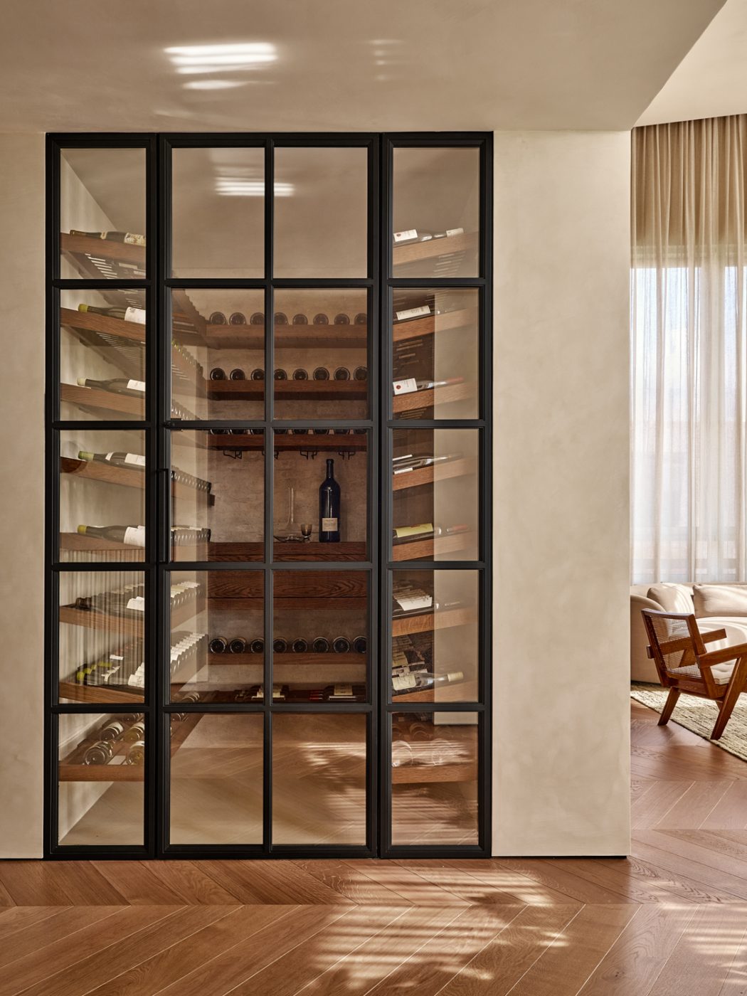 View through glass and steels door from living room into wine cellar in a Milan penthouse whose interiors are by Edo Mapelli Mozzi, founder of the design and development firm Banda.