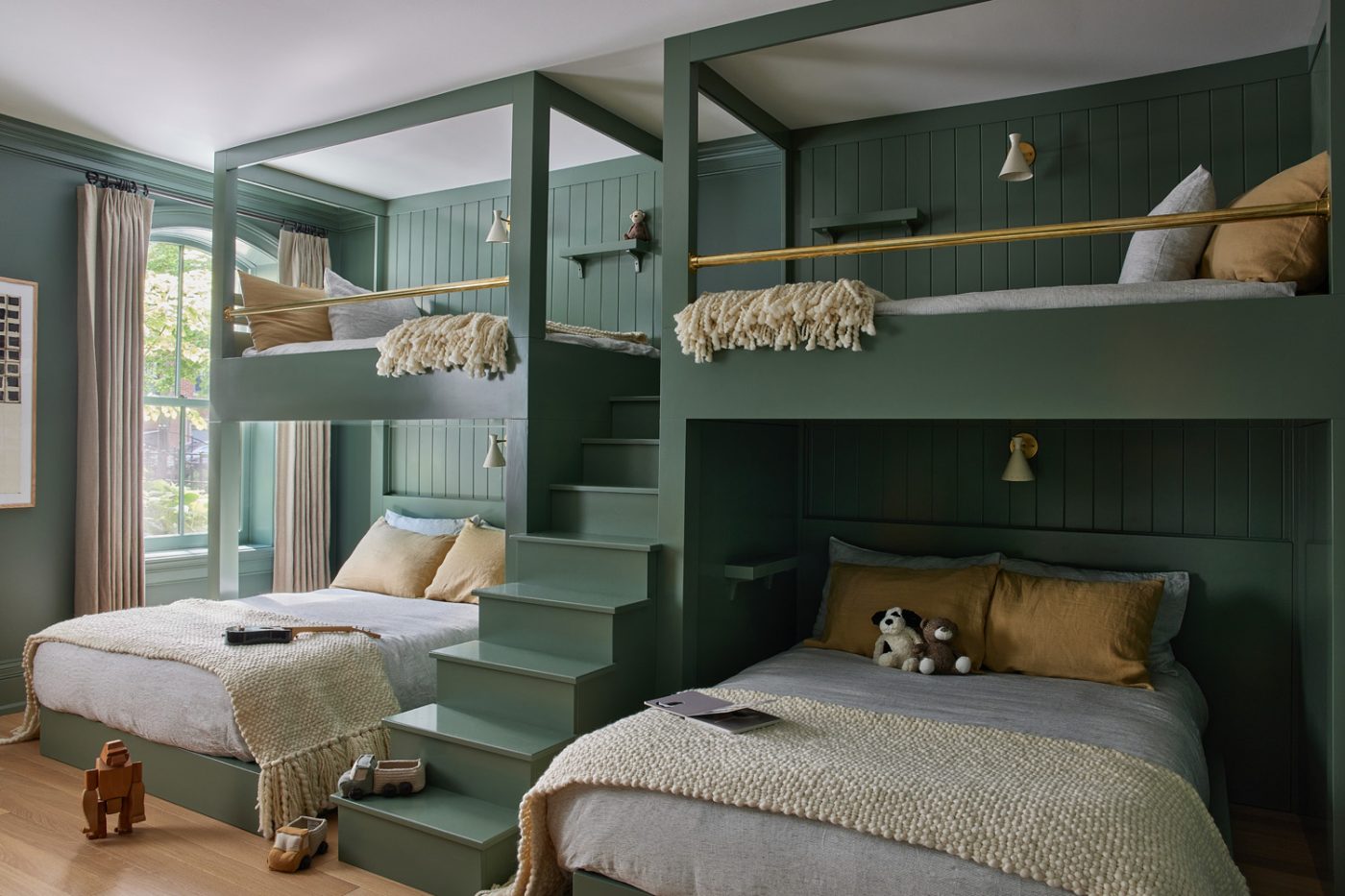 Green beadboard walls and green built-in beds and stairs in the four-bed bunk room of a historic Chicago townhouse by design partners Laura Buxbaum Gordon and Nate Berkus