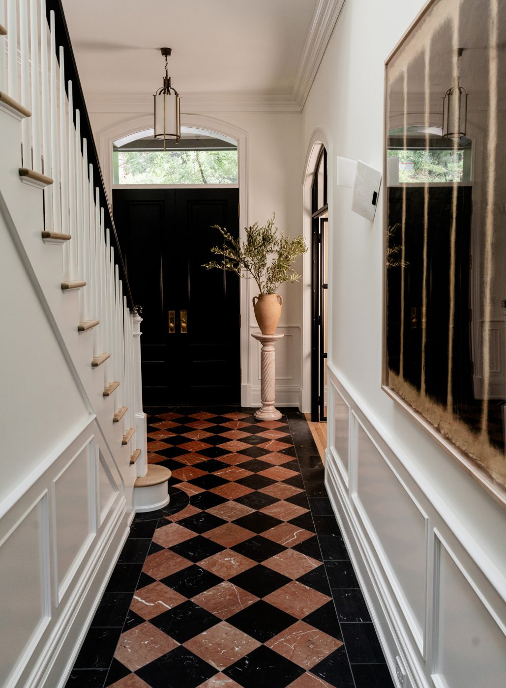 Marble checkerboard-floored stair hall in entry of a historic Chicago townhouse by design partners Laura Buxbaum Gordon and Nate Berkus