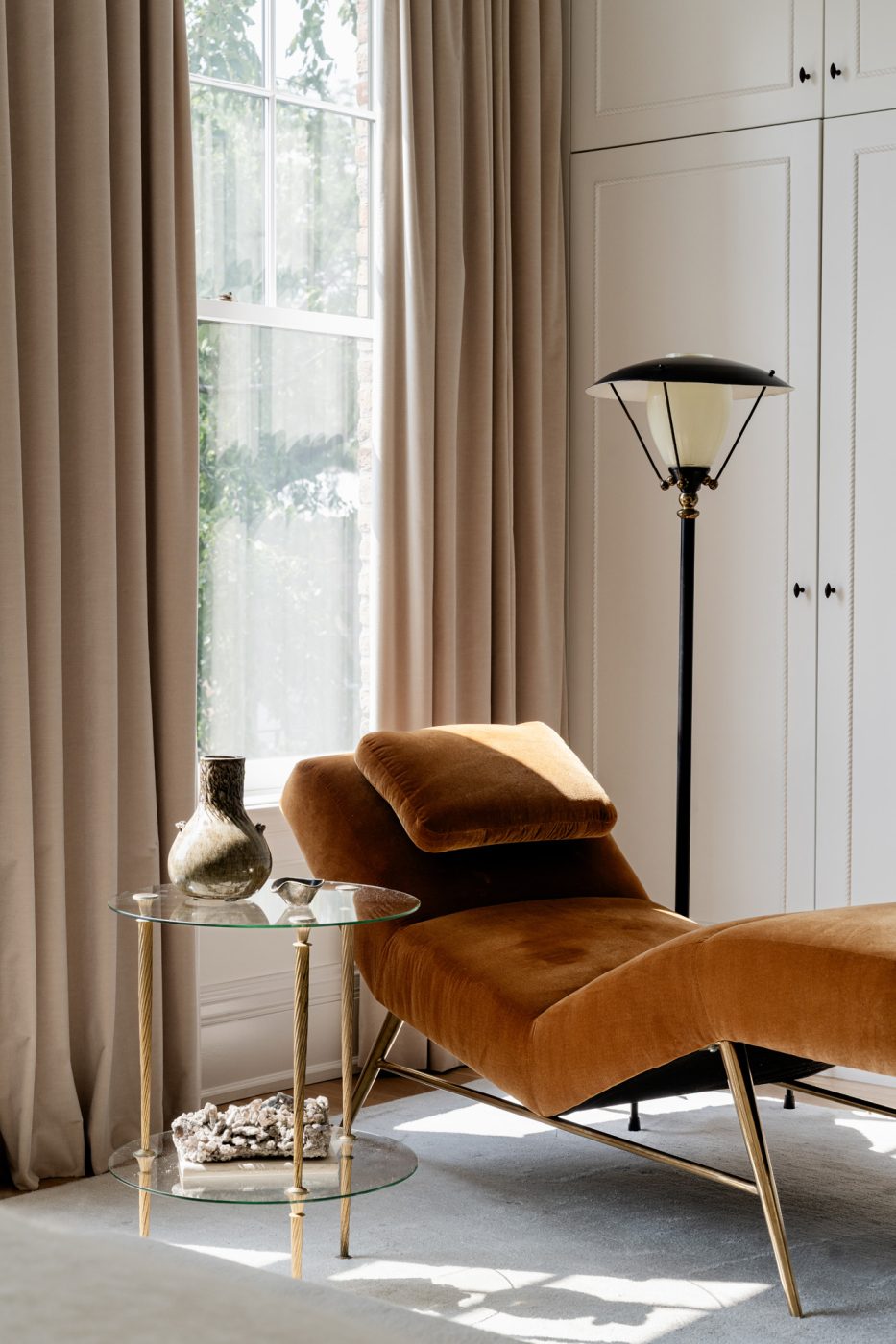 A floor lamp from Vintiques and a side table — both French and from the 1950s — flank a mid-20th-century Italian chaise from Horseman Antiques in a corner of the primary bedroom of a historic Chicago townhouse by design partners Laura Buxbaum Gordon and Nate Berkus