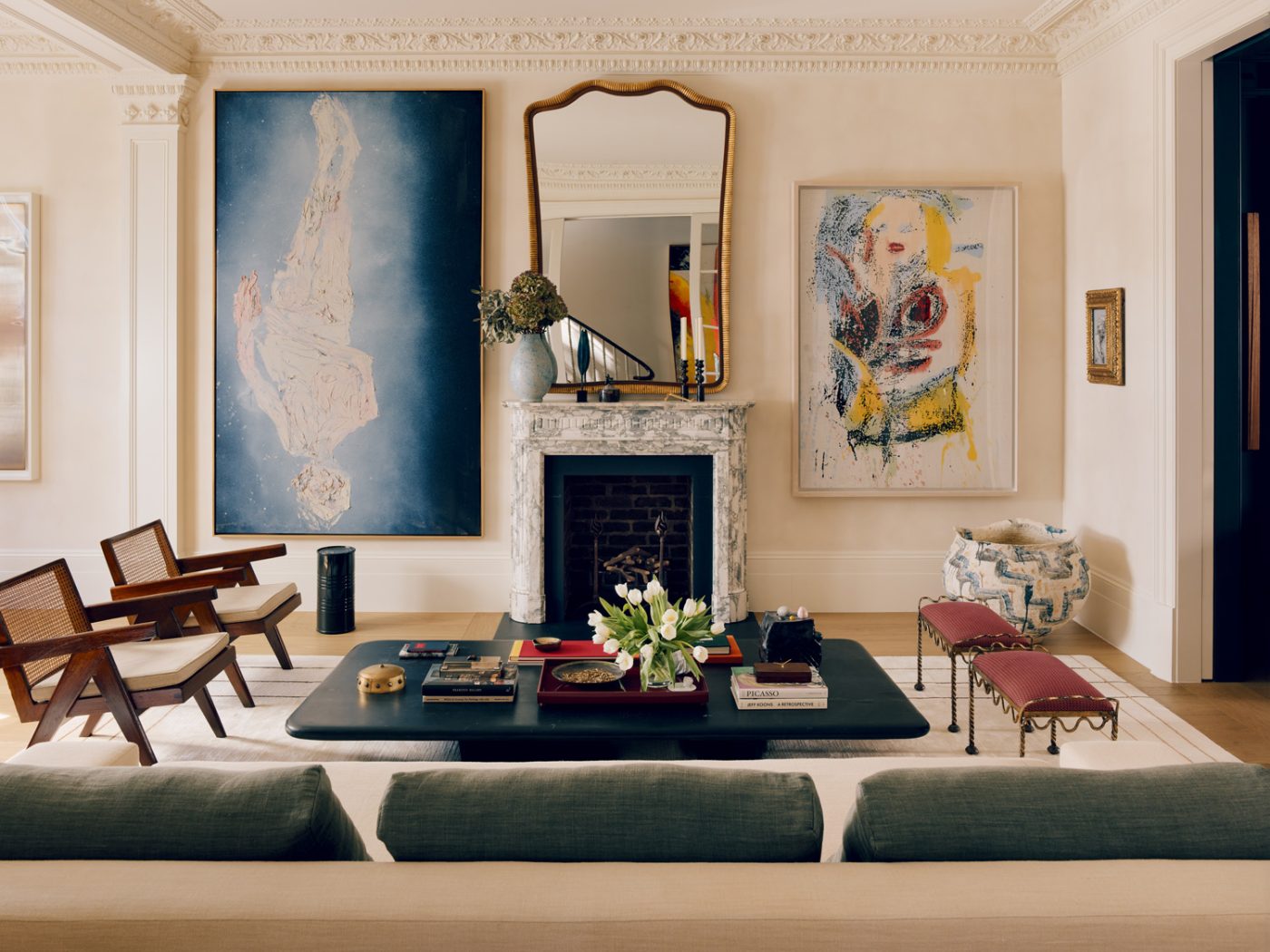 Living room of a Victorian townhouse in London's Holland Park designed by the studio De Rosee Sa and featuring a Christian Liaigre sofa, a pair of Pierre Jeanneret armchairs and vintage French stools, and paintings by Georg Baselitz (left) and Nate Lowman.