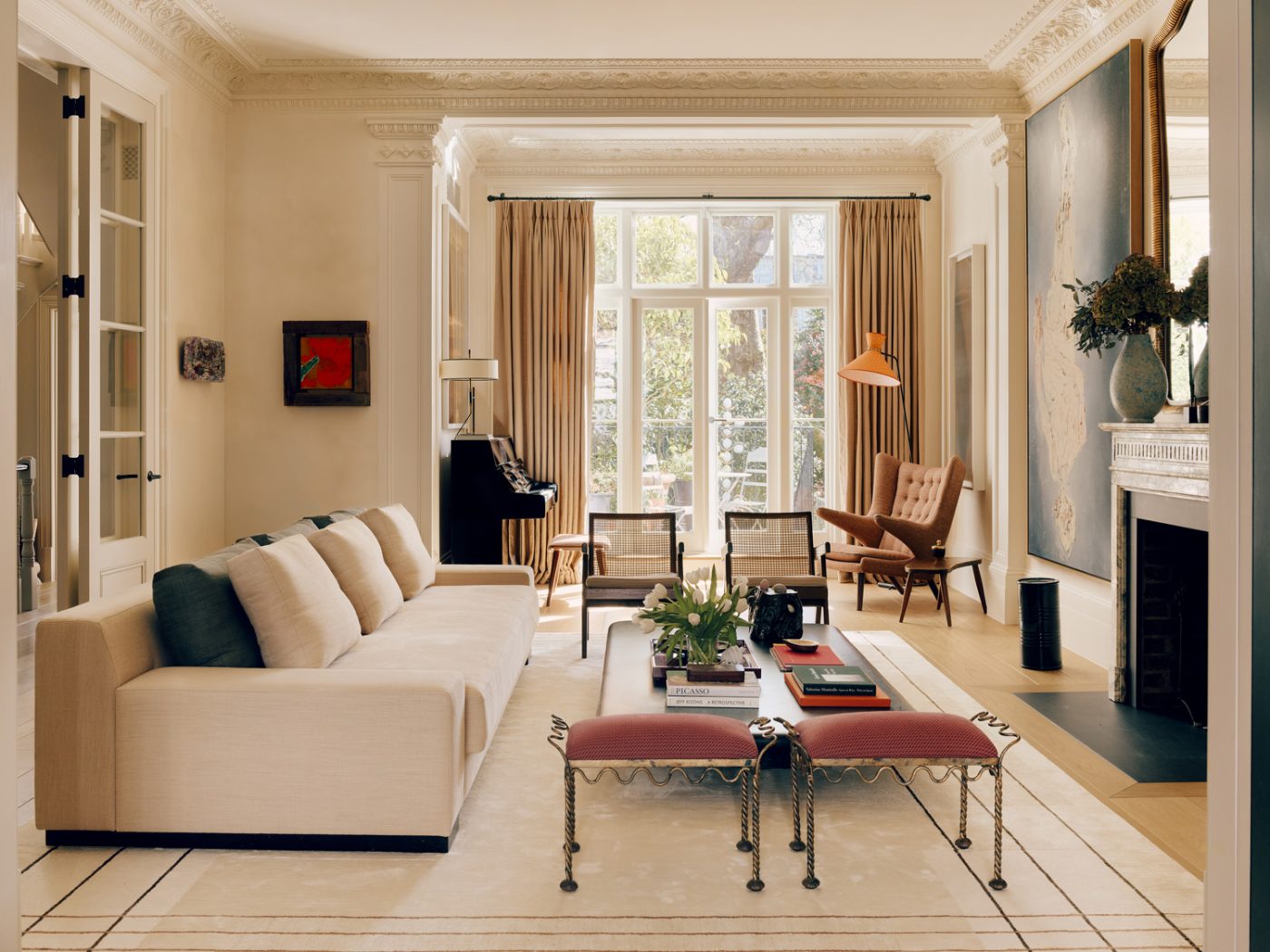 Living room of a Victorian townhouse in London's Holland Park designed by the studio De Rosee Sa and featuring a Christian Liaigre sofa, a pair of Pierre Jeanneret armchairs and vintage French stools, a Papa Bear chair by Hans Wegner and a Robert Mathieu floor lamp.