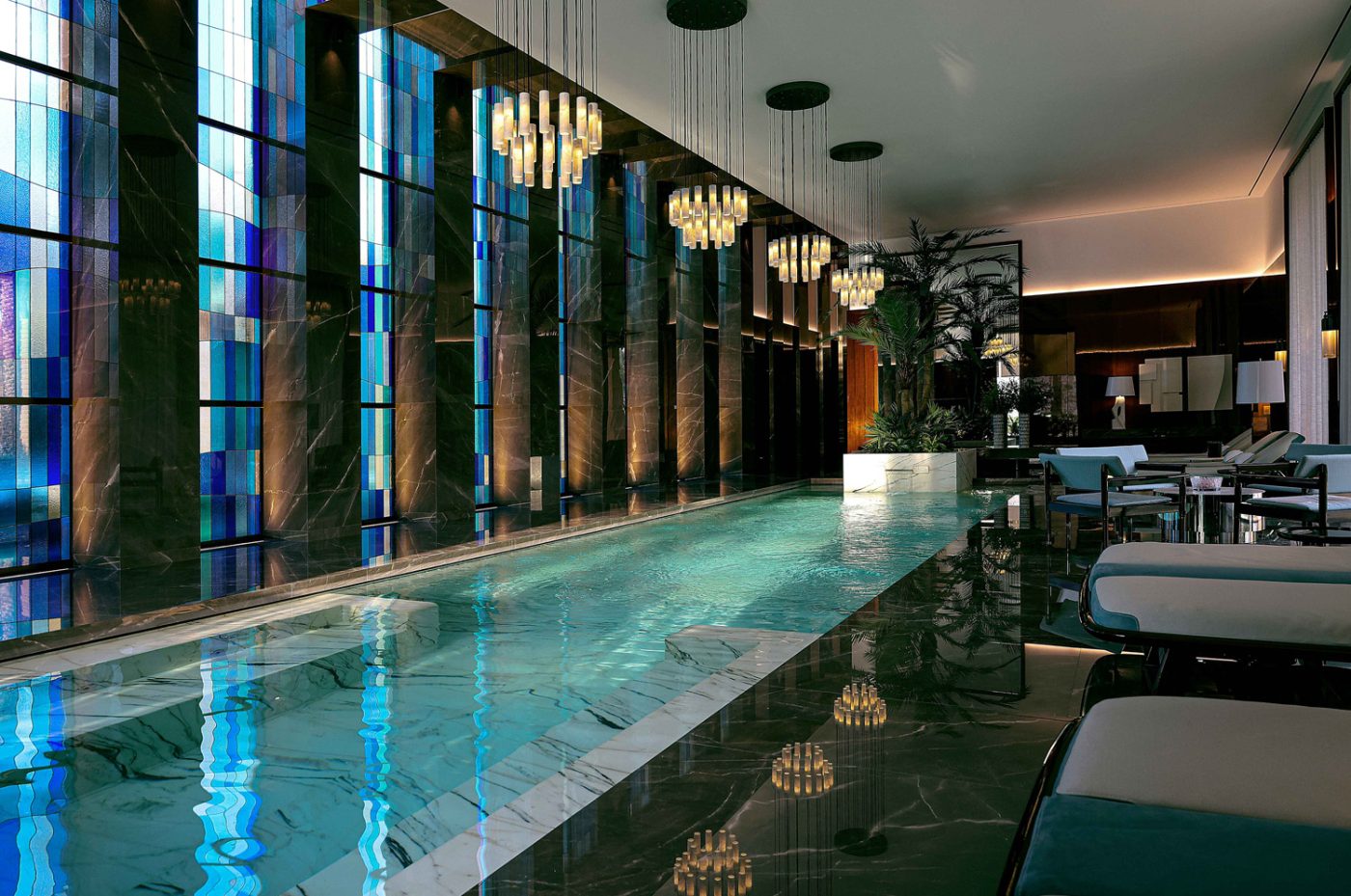 Salvatori white stone chandeliers, Willy Rizzo sconces, Massimo Castagna chaise longues and stained-glass-window walls in the indoor pool of the entertaining pavilion on a large compound in Saudi Arabia by Jacques Bec and Artur Miranda's architecture and design studio Oitoemponto