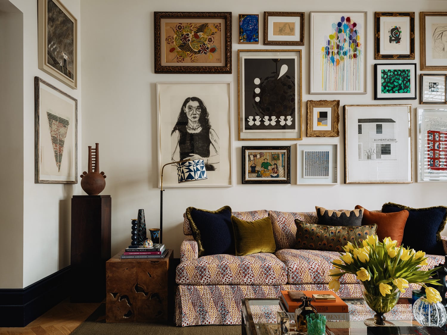 Gallery wall over custom sofa in front sitting room in the apartment in London's Kensington owned and decorated by Romanos Brihi, co-founder of the London interior design firm Studio Vero