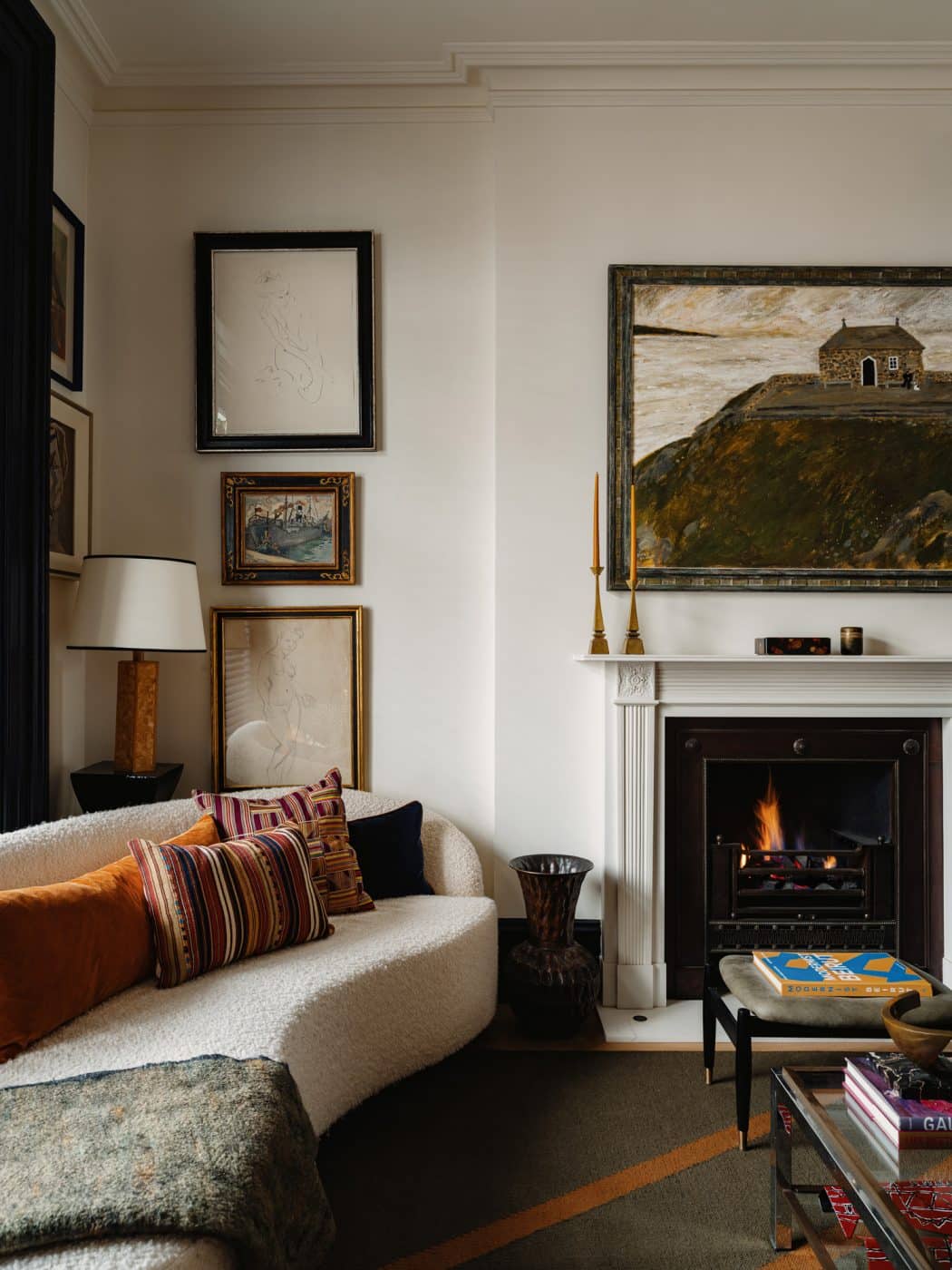 Curving boucle sofa and fireplace in the front sitting room in the apartment in London's Kensington owned and decorated by Romanos Brihi, co-founder of the London interior design firm Studio Vero