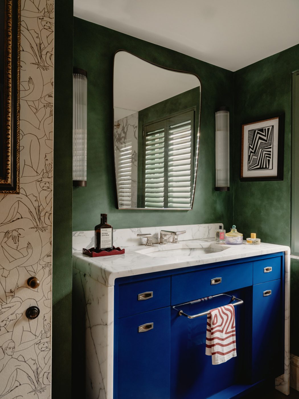 Green-walled bathroom with white-marble-framed blue vanity in the apartment in London's Kensington owned and decorated by Romanos Brihi, co-founder of the London interior design firm Studio Vero