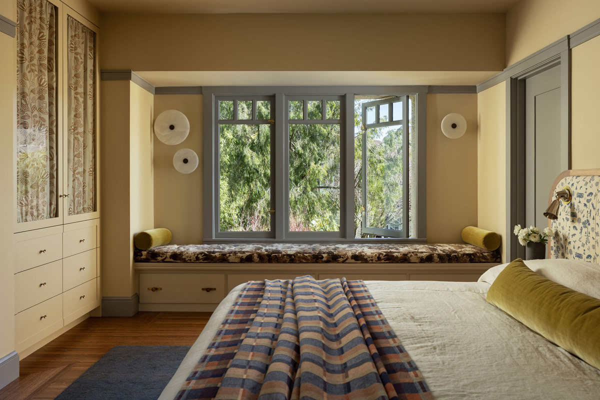 Primary bedroom of Craftsman-style house in San Francisco's Presidio designed by Katie Troutman with view into laundry room featuring Pierre Frey wallpaper