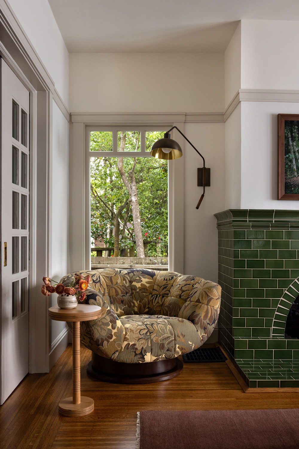 Living room of Craftsman-style house in San Francisco's Presidio designed by Katie Troutman and featuring Adrian Pearsall armchair beside a green-tiled fireplace. Beyond