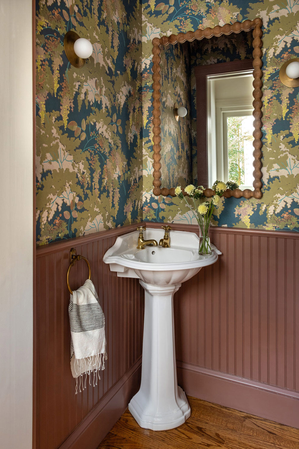Powder room of Craftsman-style house in San Francisco's Presidio designed by Katie Troutman and featuring botanical Frondaisons wallpaper from the French company Isidore Leroy over beadboard wainscoting painted mauve. Allied Maker sconces are on either side of bobbin-framed mirror