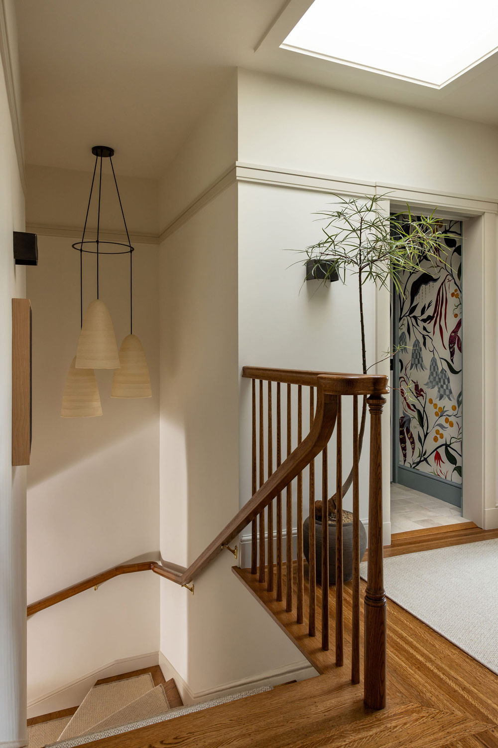 Staircase landing of Craftsman-style house in San Francisco's Presidio designed by Katie Troutman with view into laundry room featuring Pierre Frey wallpaper