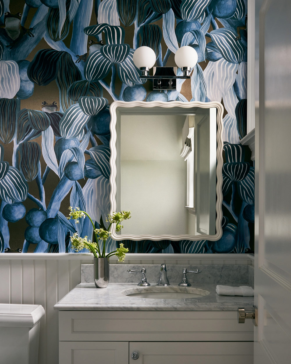 blue abstracted botanical wallpaper, white cabinets and marble counters in powder room of Southampton house with interiors by Janine Carendi MacMurray or Area Interior Design