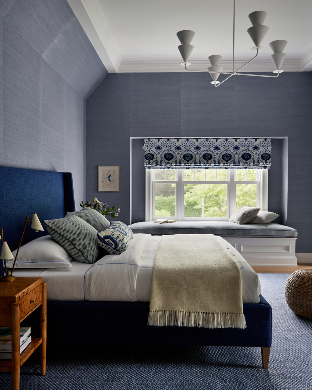 Blue guest room with a plaster chandelier and patterned roman shade in Southampton house with interiors by Janine Carendi MacMurray or Area Interior Design