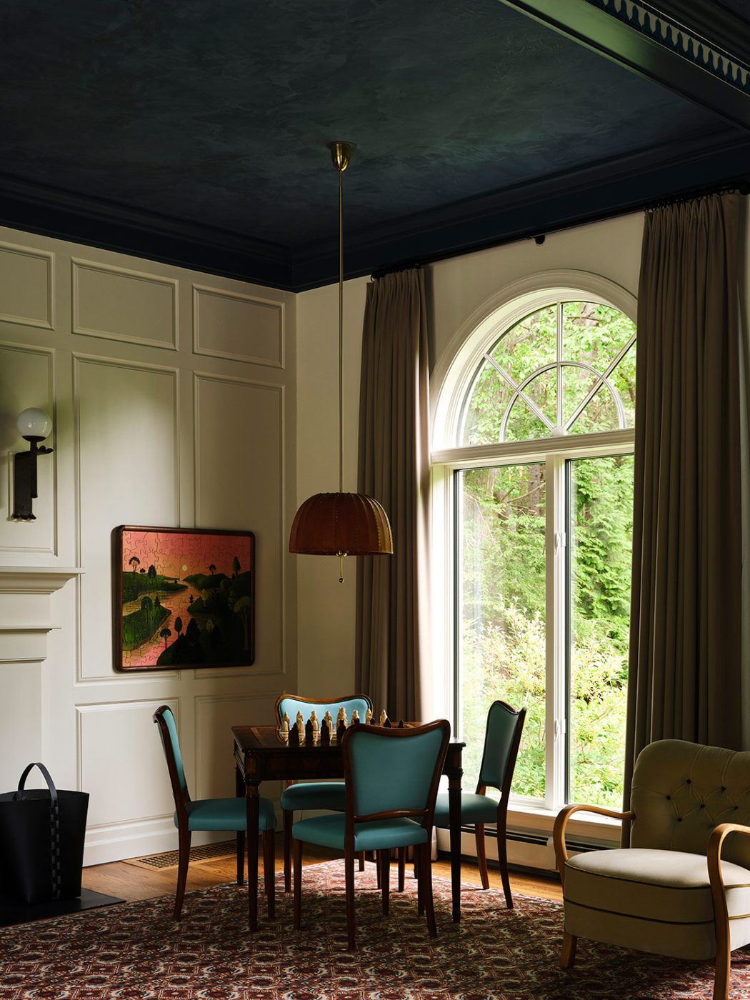 a vintage games table and a set of four Danish dining chairs from the Somerset House sit under a leather Hans-Agne Jakobsson chandelier from the 1960s in the great room of a New Hampshire house with interiors by designer Zoe Feldman