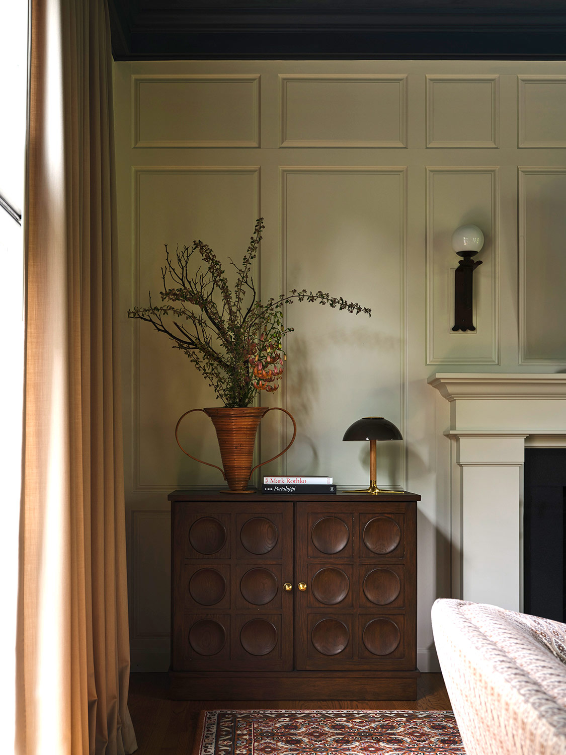 Contemporary bar cabinet next to white fireplace in the great room of a New Hampshire house with interiors by designer Zoe Feldman