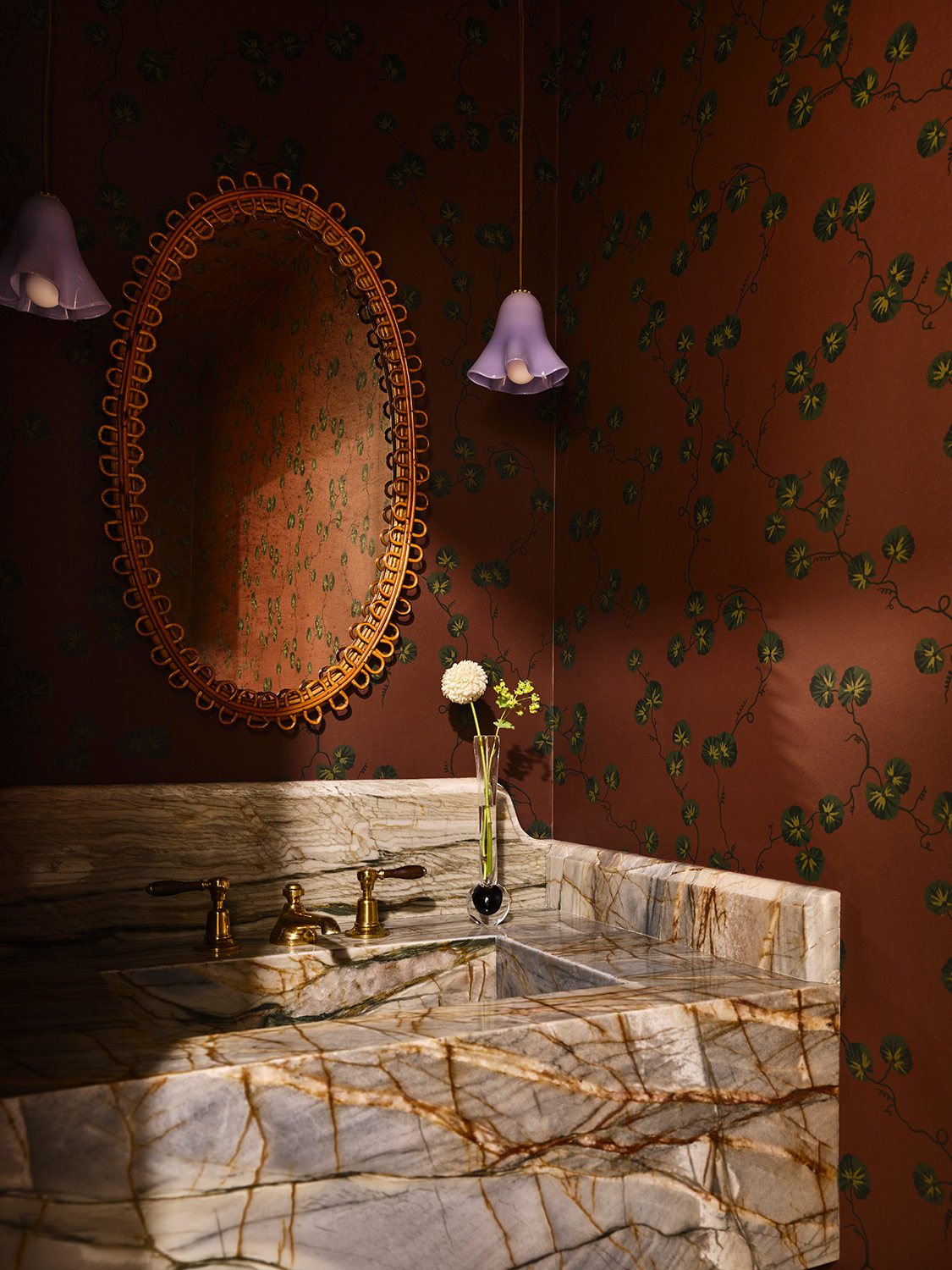 Dark red-brown wallpaper and expressive marble sink and a French mid-century mirror in the powder room of a New Hampshire house with interiors by designer Zoe Feldman