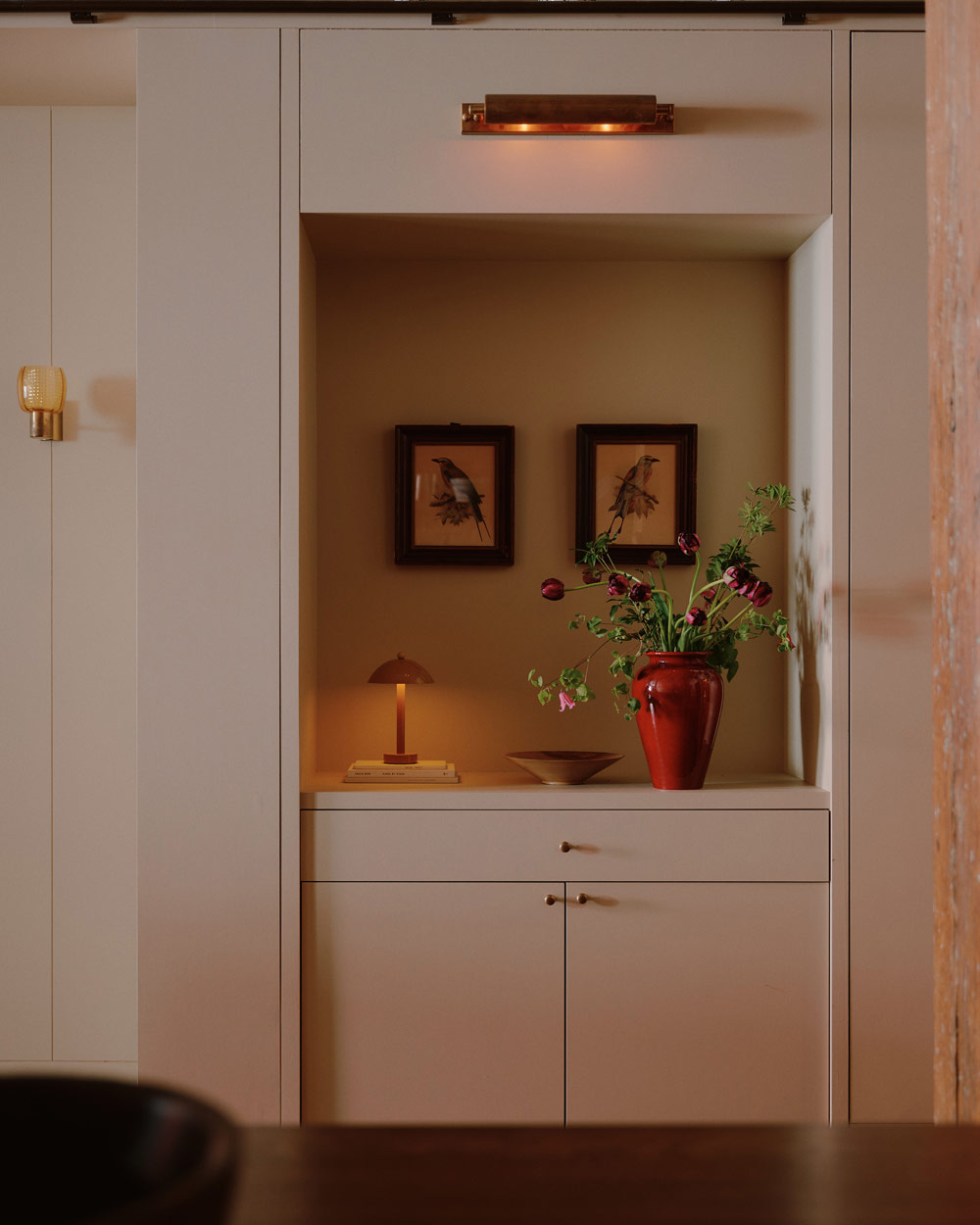 Two 1930s lithographs by Dutch illustrator J.G. Keulemans are mounted in a niche above an In Common With table lamp in the entryway of a downtown New York loft designed by Sarah Zames and Colin Stief, of the Brooklyn-based studio General Assembly