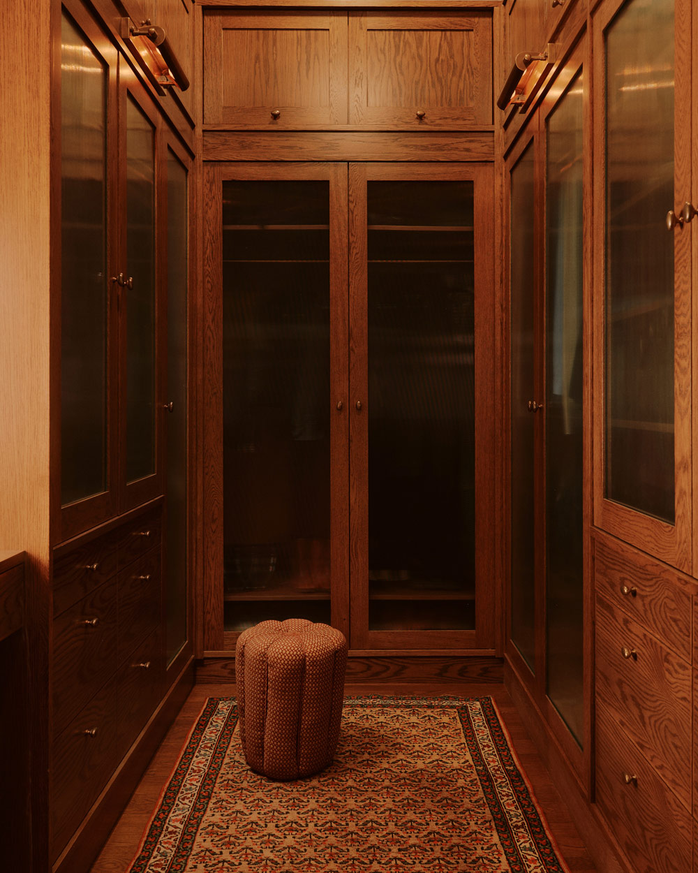 dressing room with millwork made of fumed oak, a vintage stool sourced from Morentz and a vintage rug from Persian Gallery in a downtown New York loft designed by Sarah Zames and Colin Stief, of the Brooklyn-based studio General Assembly
