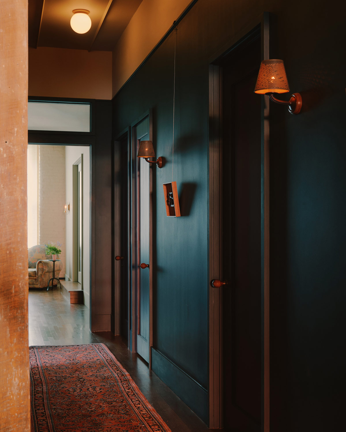Darkly painted hallway with storage closet doors and oriental pink runner in a downtown New York loft designed by Sarah Zames and Colin Stief, of the Brooklyn-based studio General Assembly