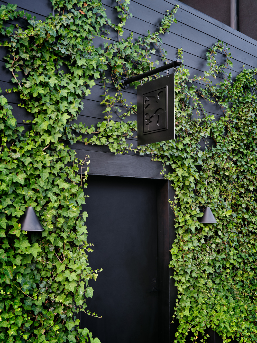 Black painted, vine coffered exterior street level entry door to the headquarters of the Brooklyn garden design firm Harrison Green