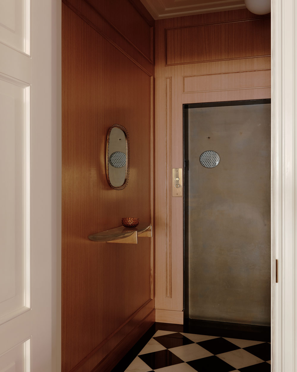 Elevator vestibule with wood-paneled walls and black-and-white checkerboard floors in a duplex apartment on New York's Park Avenue designer by Bryan O'Sullivan